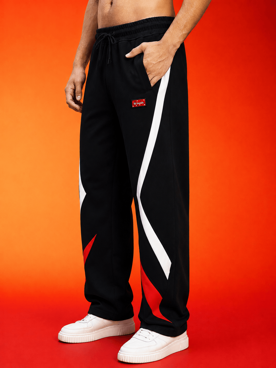 METROPOLITAN CONTRAST GRAPHIC JOGGERS BLACK MULTI featuring bold graphic design and a relaxed fit against an orange background.