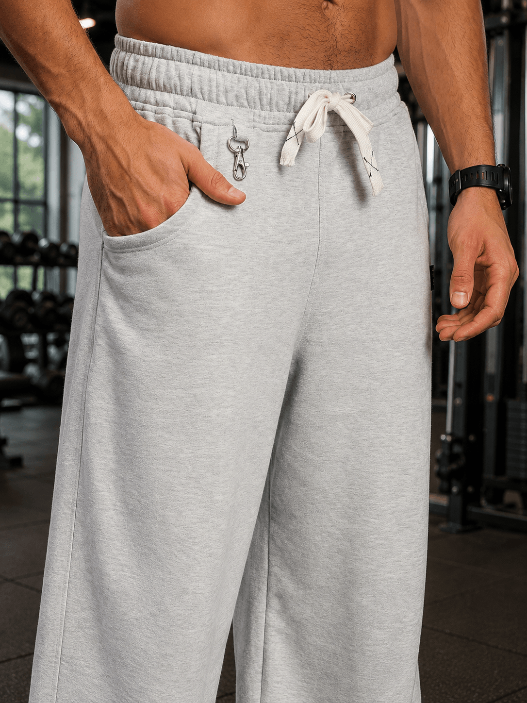 CARABINER UTILITY BAGGY JOGGERS MELANGE GREY close-up showing pocket and carabiner detail on a fitness background.