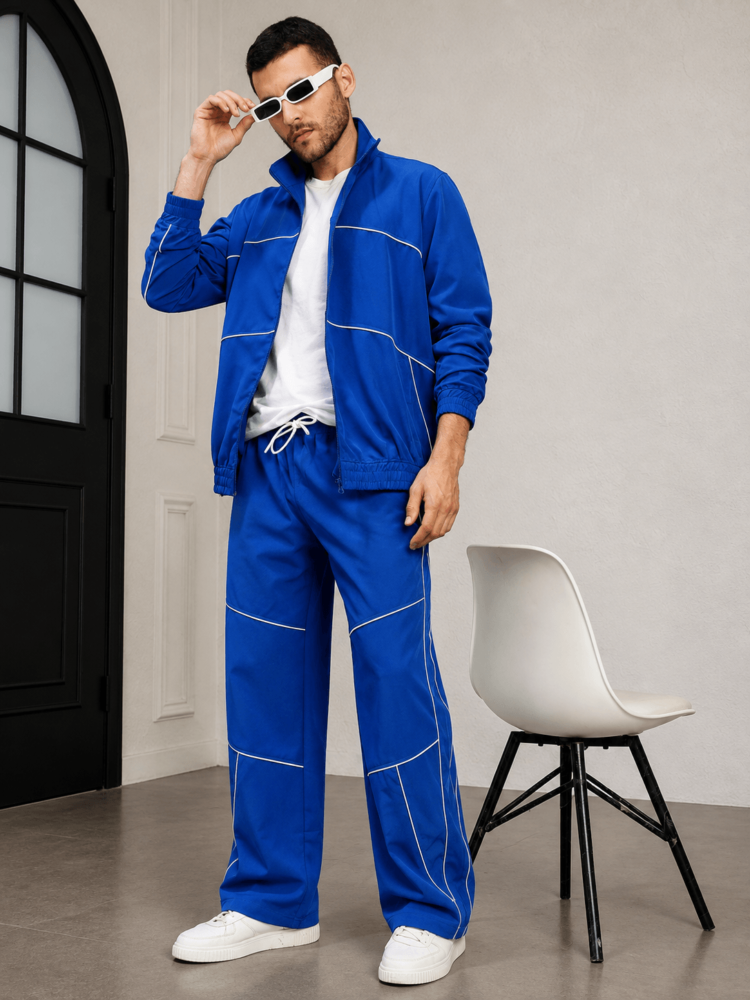 RAIDER CO-ORD SET BLUE WITH WHITE ACCENTS model wearing matching blue tracksuit with white accents and sunglasses.