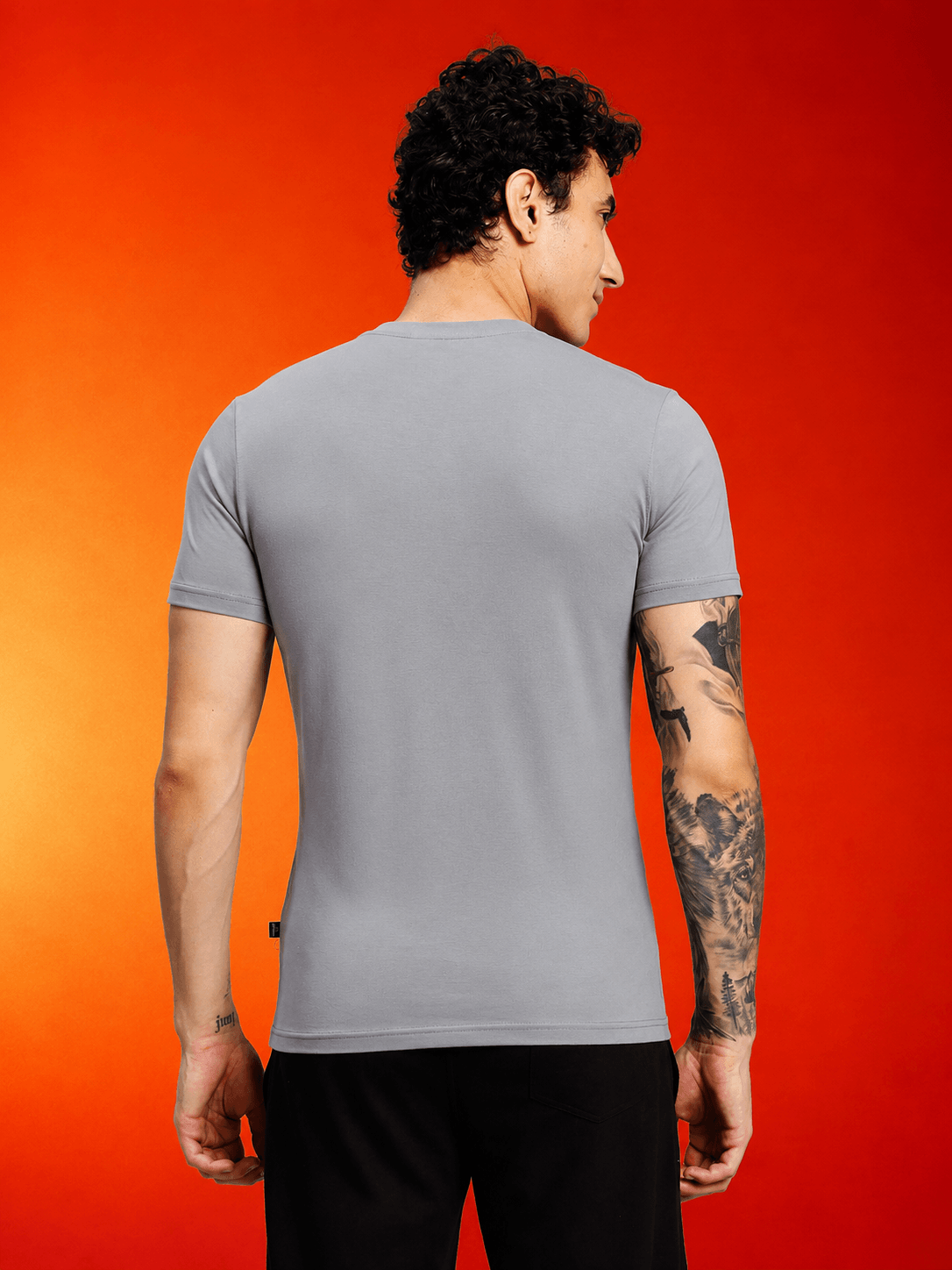 CORE SHORT REGULAR FIT T-SHIRT GREY worn by a man, showcasing the back design against an orange background.