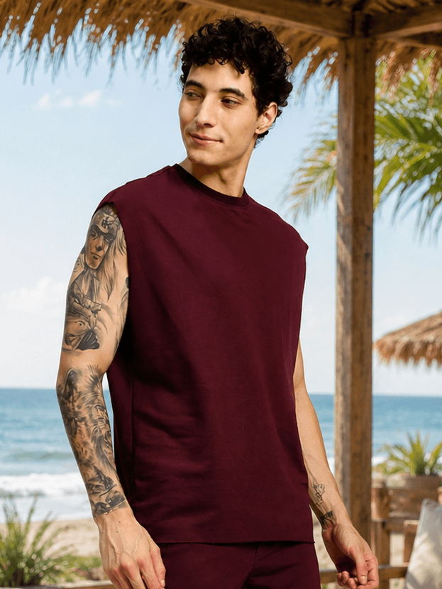 DRIVE MONOCHROME SLEEVELESS T-SHIRT MAROON worn by model at beach with palm trees in background