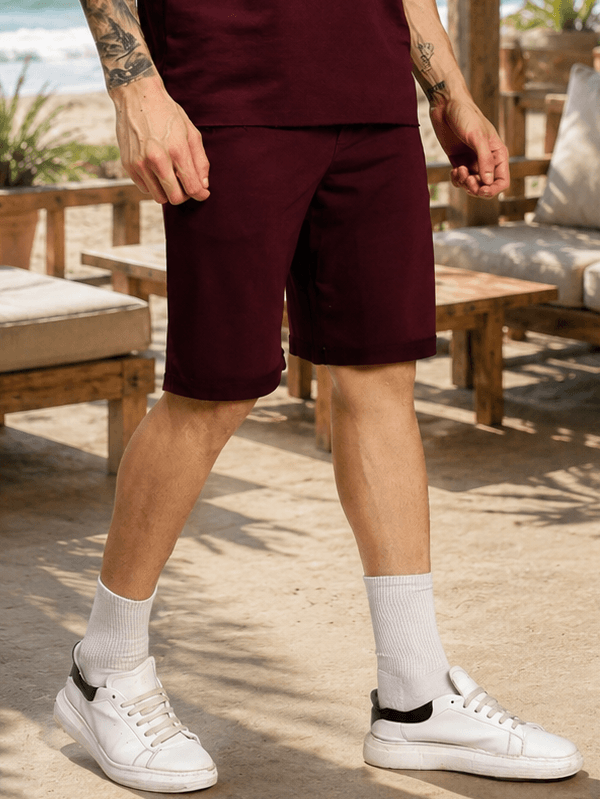 DRIVE MONOCHROME RELAXED FIT SHORTS MAROON showcased in a casual beach setting, perfect for summer outfits.