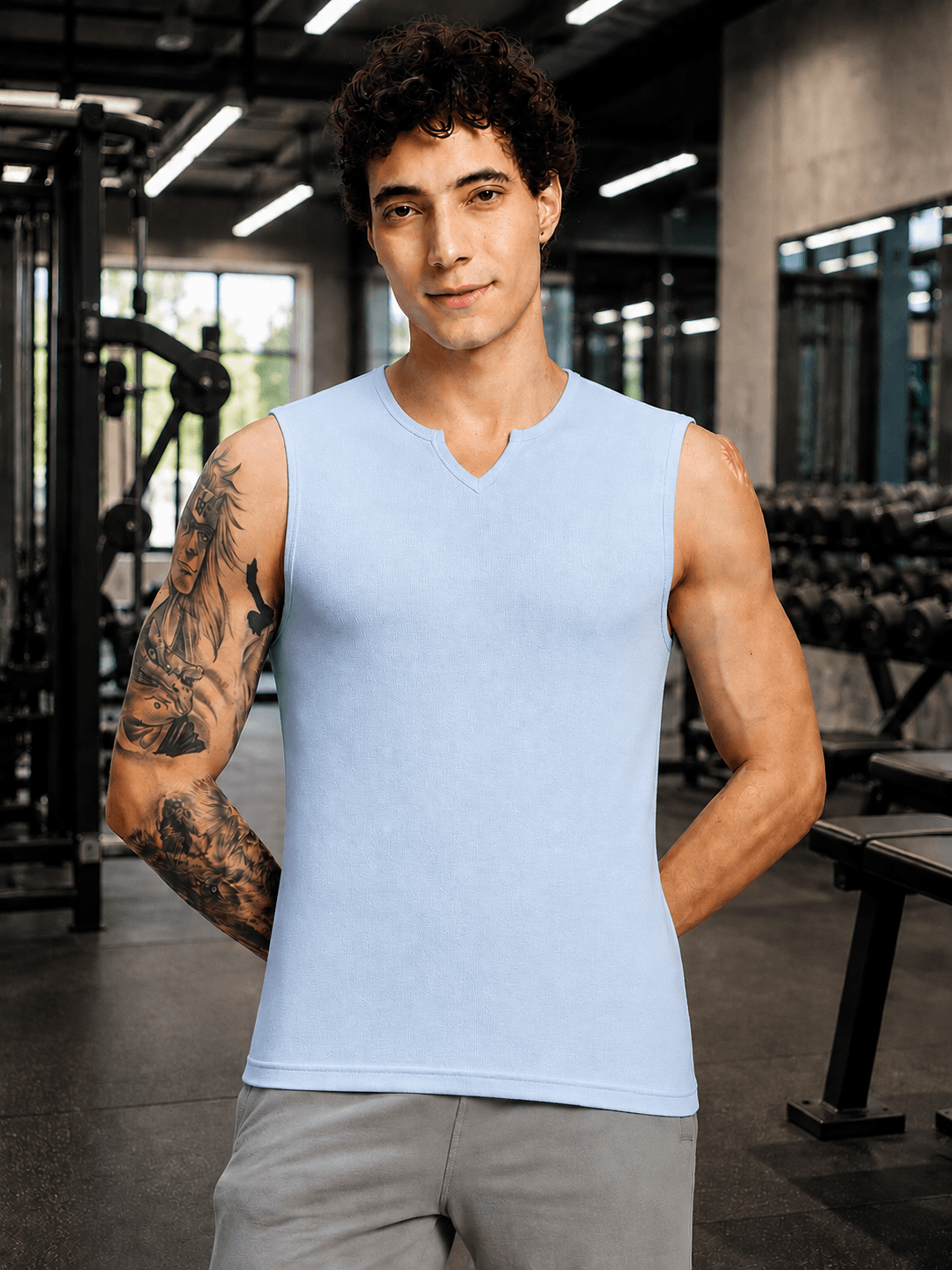 MUSCLE FIT SLEEVELESS GYM T-SHIRT SKY BLUE on a muscular man in a gym setting, showcasing a modern fitness style.