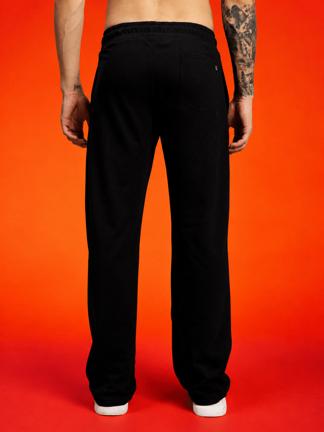 WILDCARD RAW-CANVAS GRAPHIC JOGGERS BLACK, back view of black joggers on a man against an orange background.