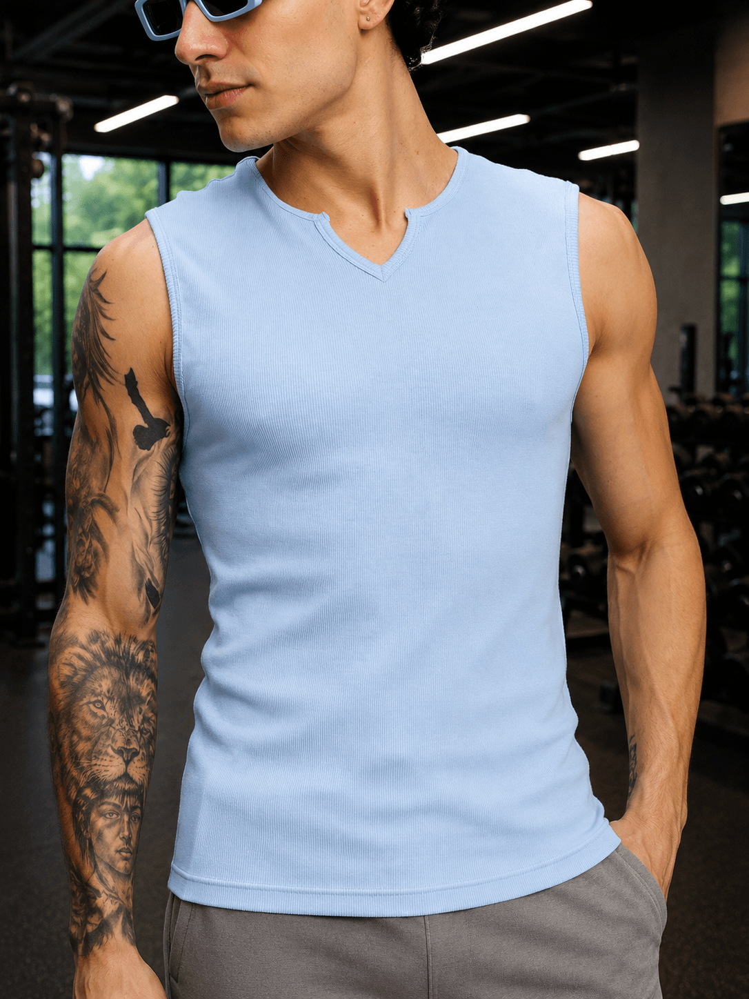 MUSCLE FIT SLEEVELESS GYM T-SHIRT SKY BLUE shown on a fit man with tattoos in a gym setting.