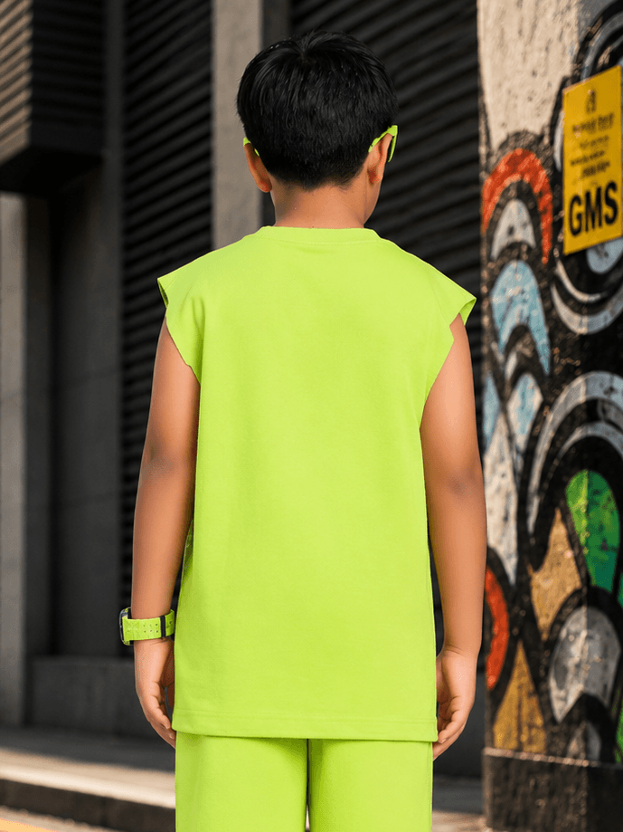 Boy wearing NEON RUSH SLEEVELESS T-SHIRT FOR BOYS GIRLS NEON GREEN standing against a graffiti wall.