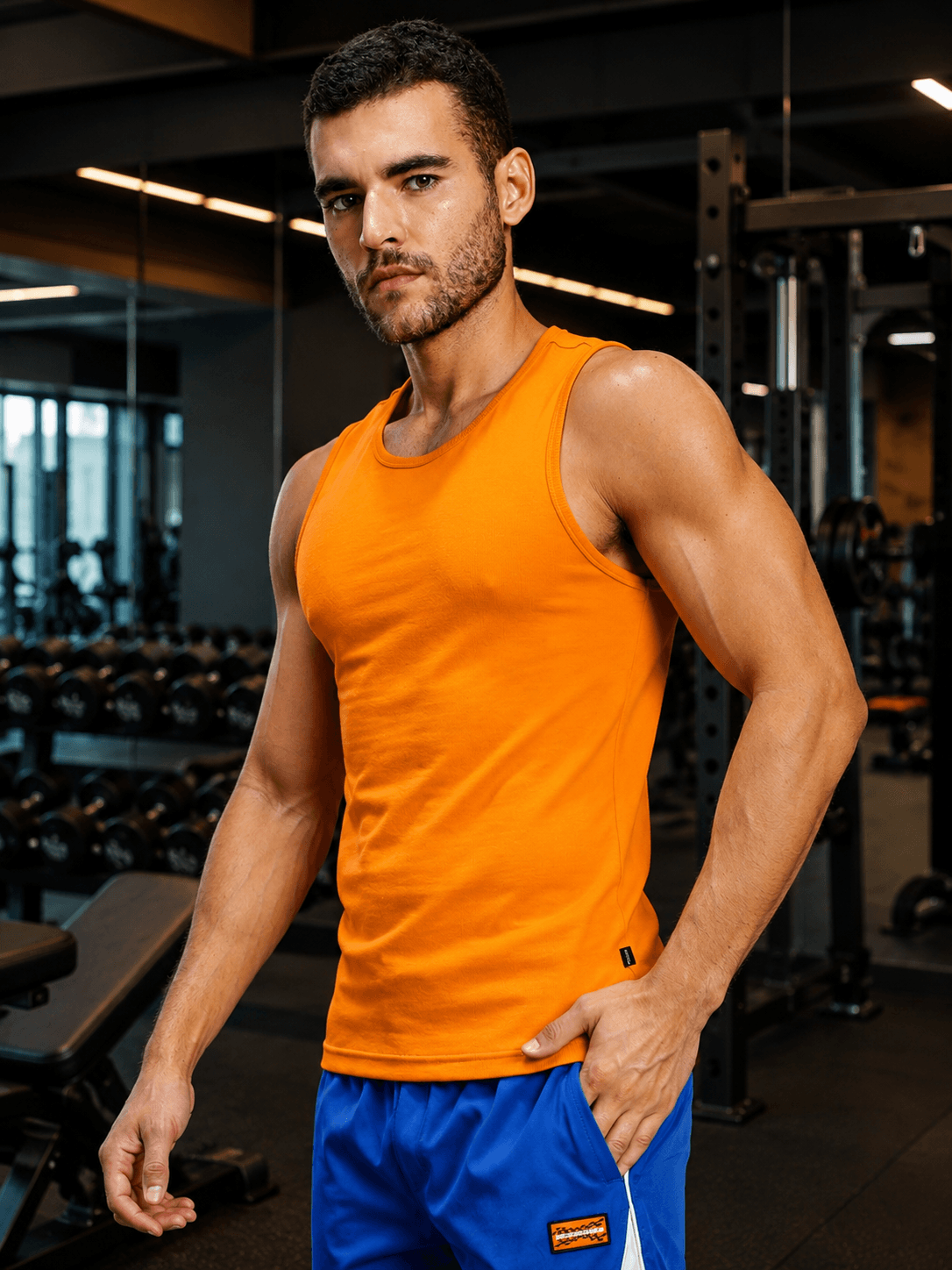 Muscle fit bodybuilding gym t-shirt orange worn by a man in a fitness center, showcasing a bold athletic style.