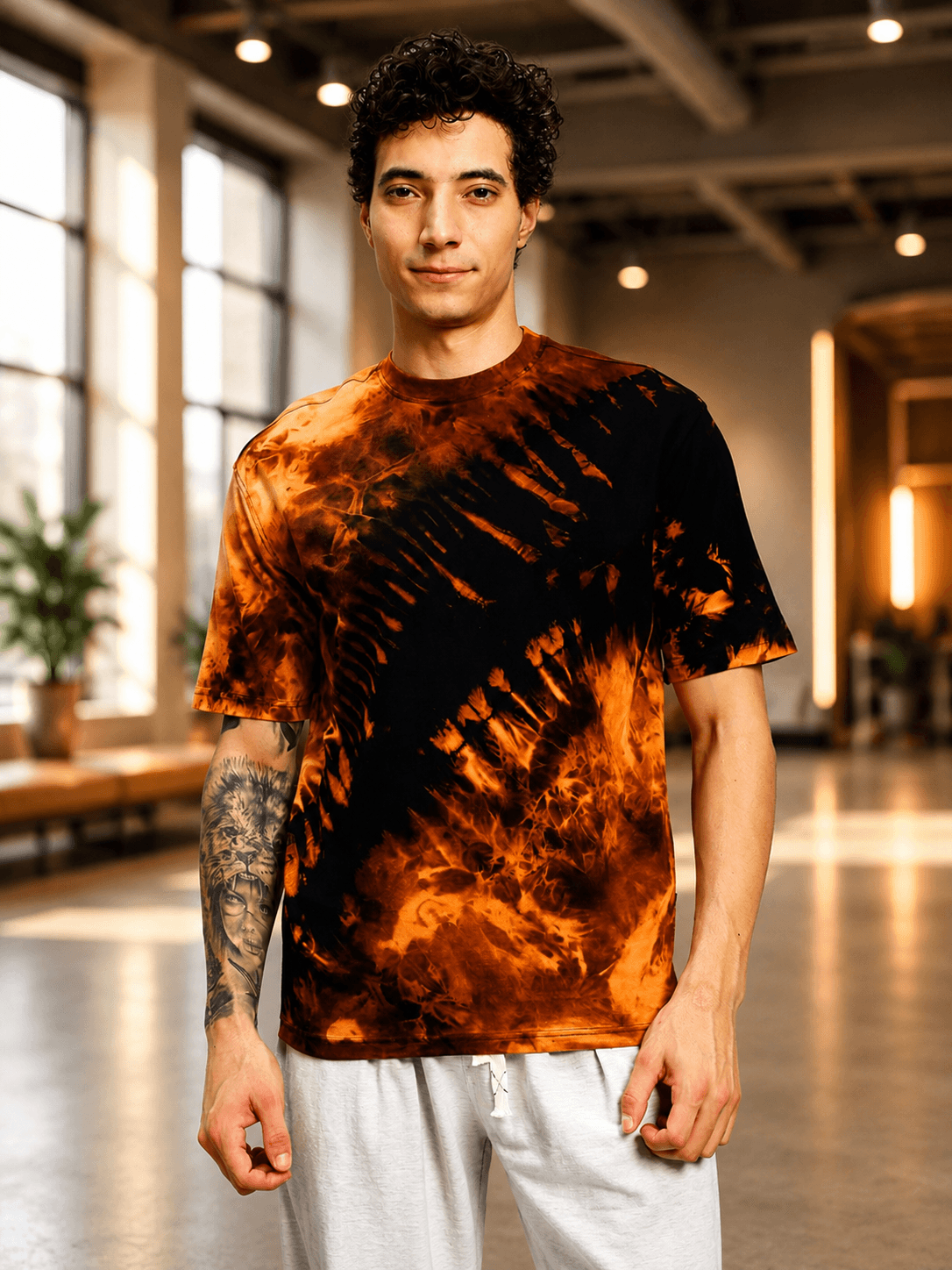 SOLAR TIE-DYE T-SHIRT BLACK FIRE ORANGE worn by a model in a bright room, showcasing its vibrant design.