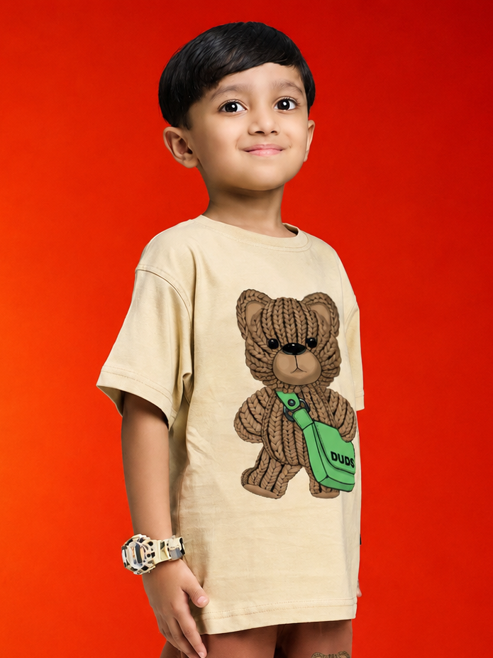 LITTLE EXPLORER TEDDY T-SHIRT FOR BOYS GIRLS BEIGE worn by a smiling boy, showcasing a playful teddy bear design.