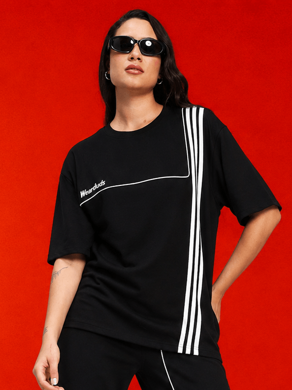 WOMEN YOUTH CONTREST PIPING T-SHIRT BLACK modeled by a woman in sunglasses against a vibrant red background.