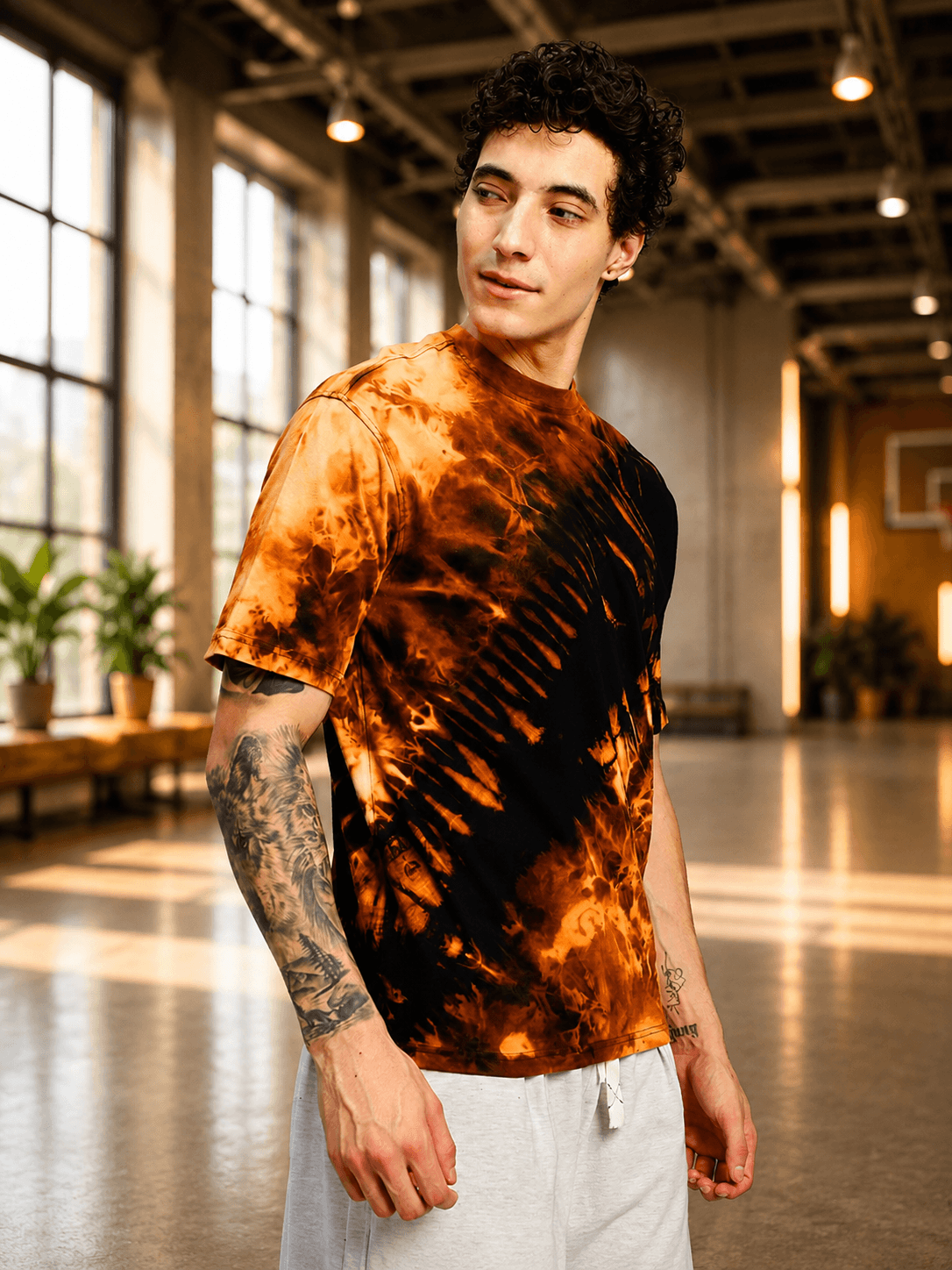 Model wearing SOLAR TIE-DYE T-SHIRT BLACK FIRE ORANGE in a bright indoor setting.