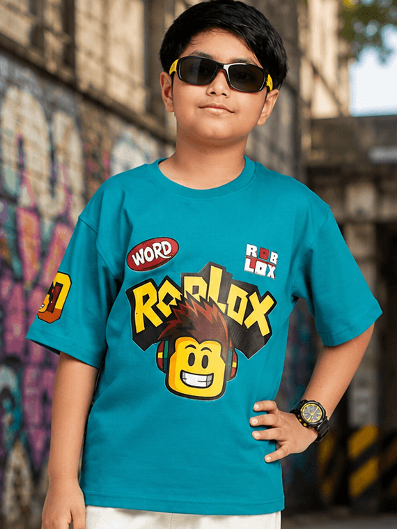 JUNIOR T-SHIRT FOR BOYS GIRLS BLUE worn by a boy with sunglasses and a colorful Roblox graphic.