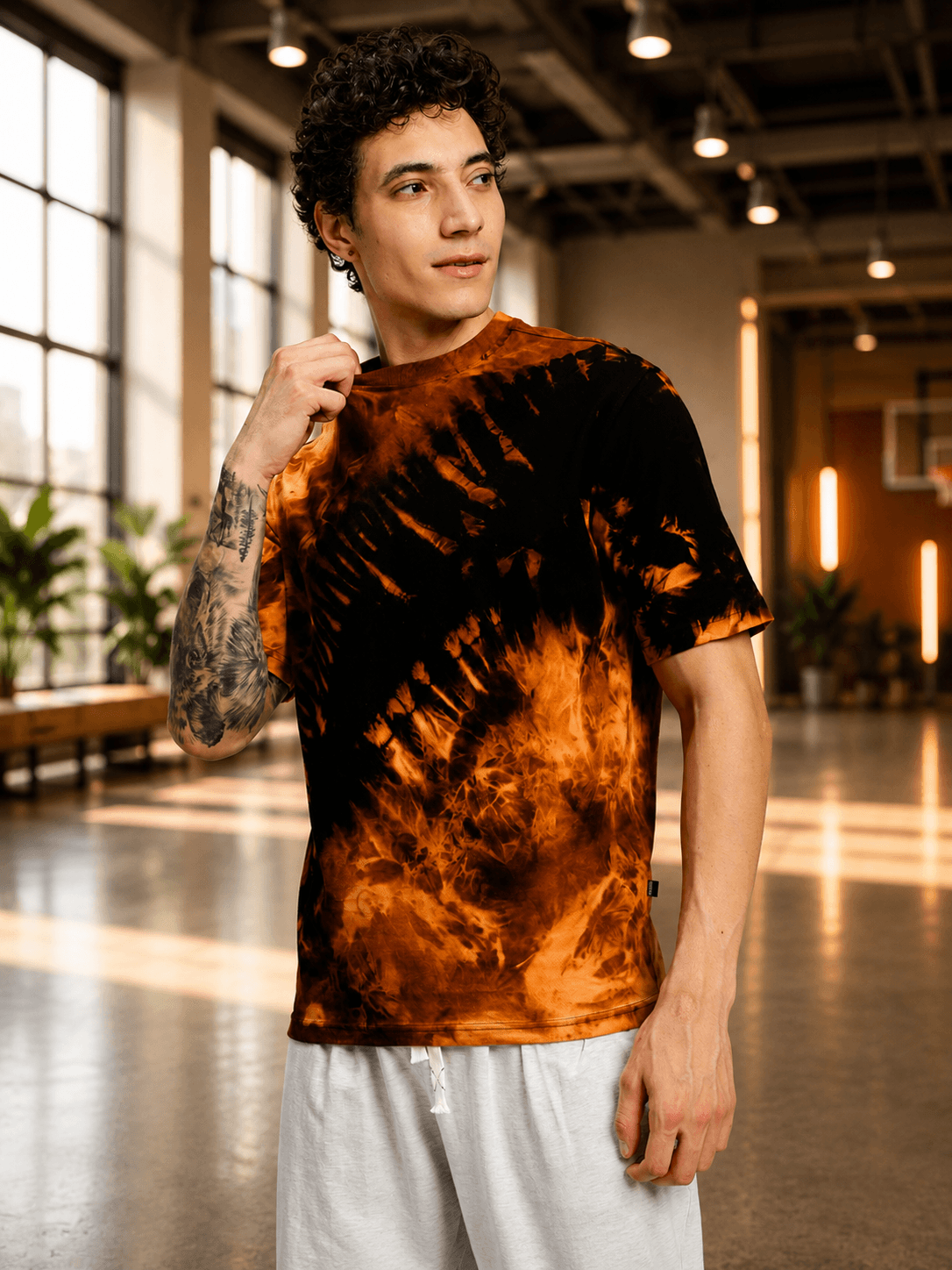 SOLAR TIE-DYE T-SHIRT BLACK FIRE ORANGE modeled by a young man in a stylish urban setting.
