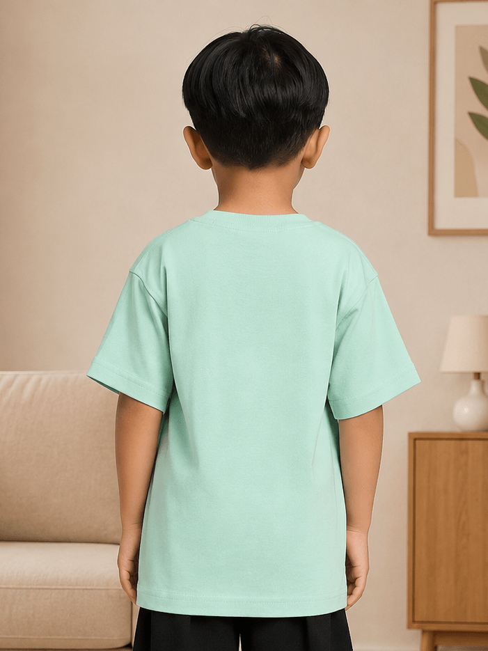 Back view of a child wearing a FUN MONSTER GRAPHIC T-SHIRT FOR BOYS GIRLS GREEN in a cozy indoor setting.