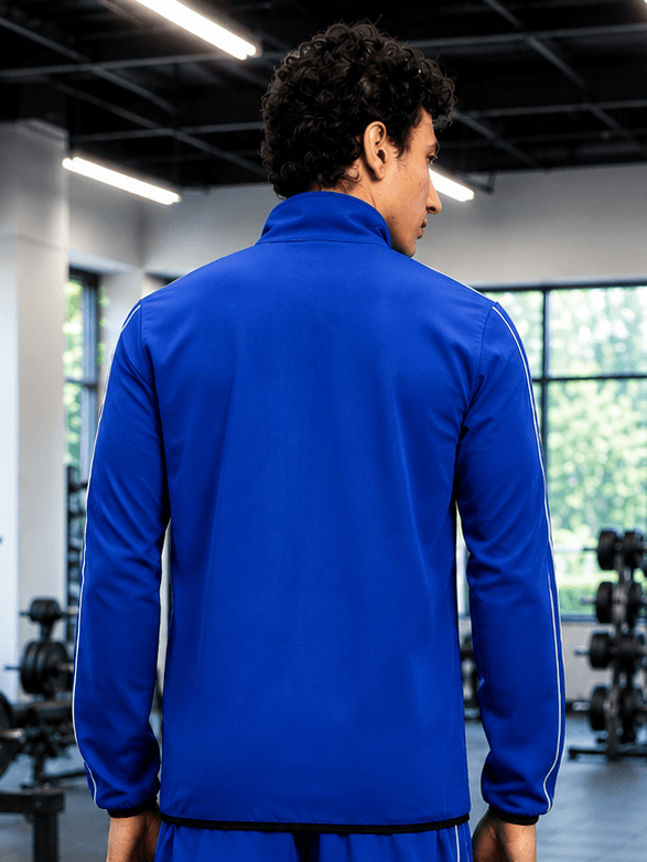 Back view of a model wearing the RELIGHT RELAXED FIT JACKET BLUE in a gym setting.