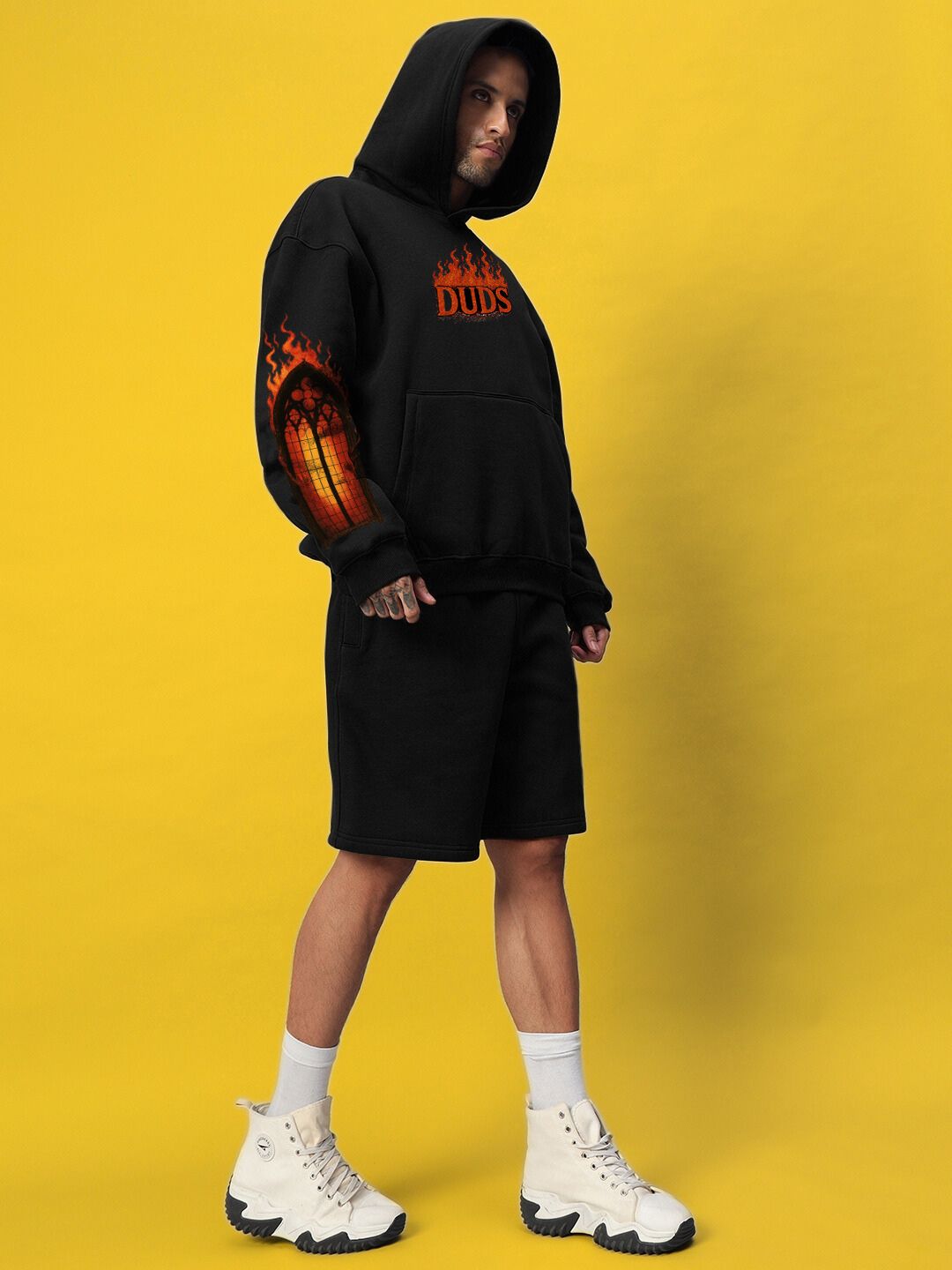 Model wearing FIRE NEVER KILLS THE LIGHT FLEECE CO-ORD BLACK with bold graphics and street-luxe design on a vibrant yellow background.