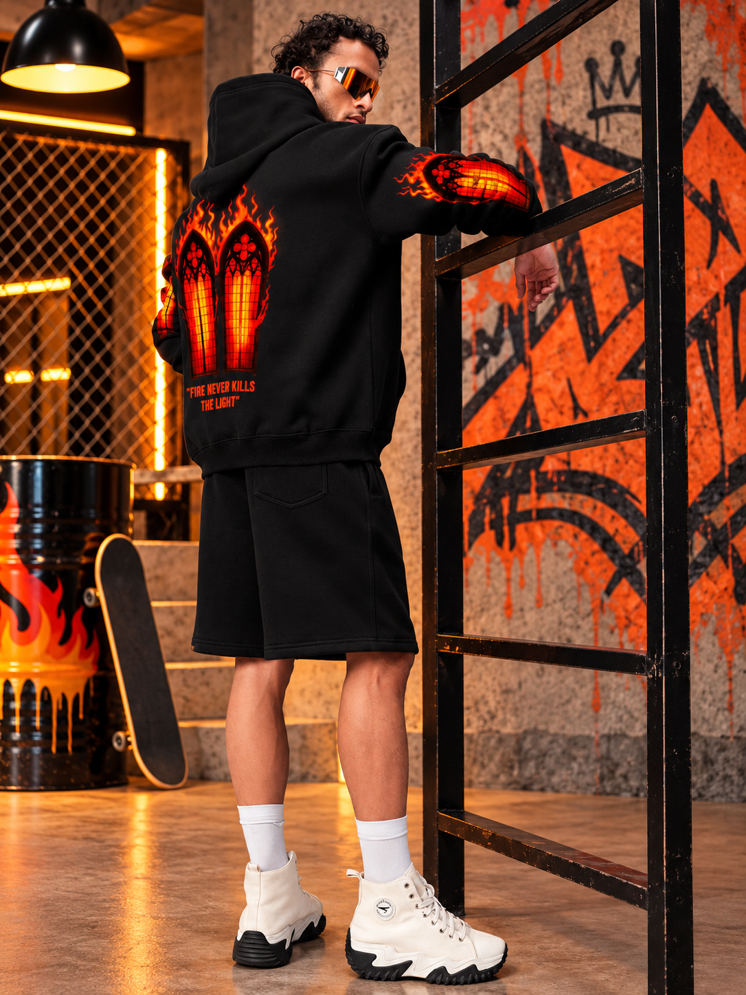 FIRE NEVER KILLS THE LIGHT FLEECE CO-ORD BLACK worn by man with flame graphic hoodie and shorts