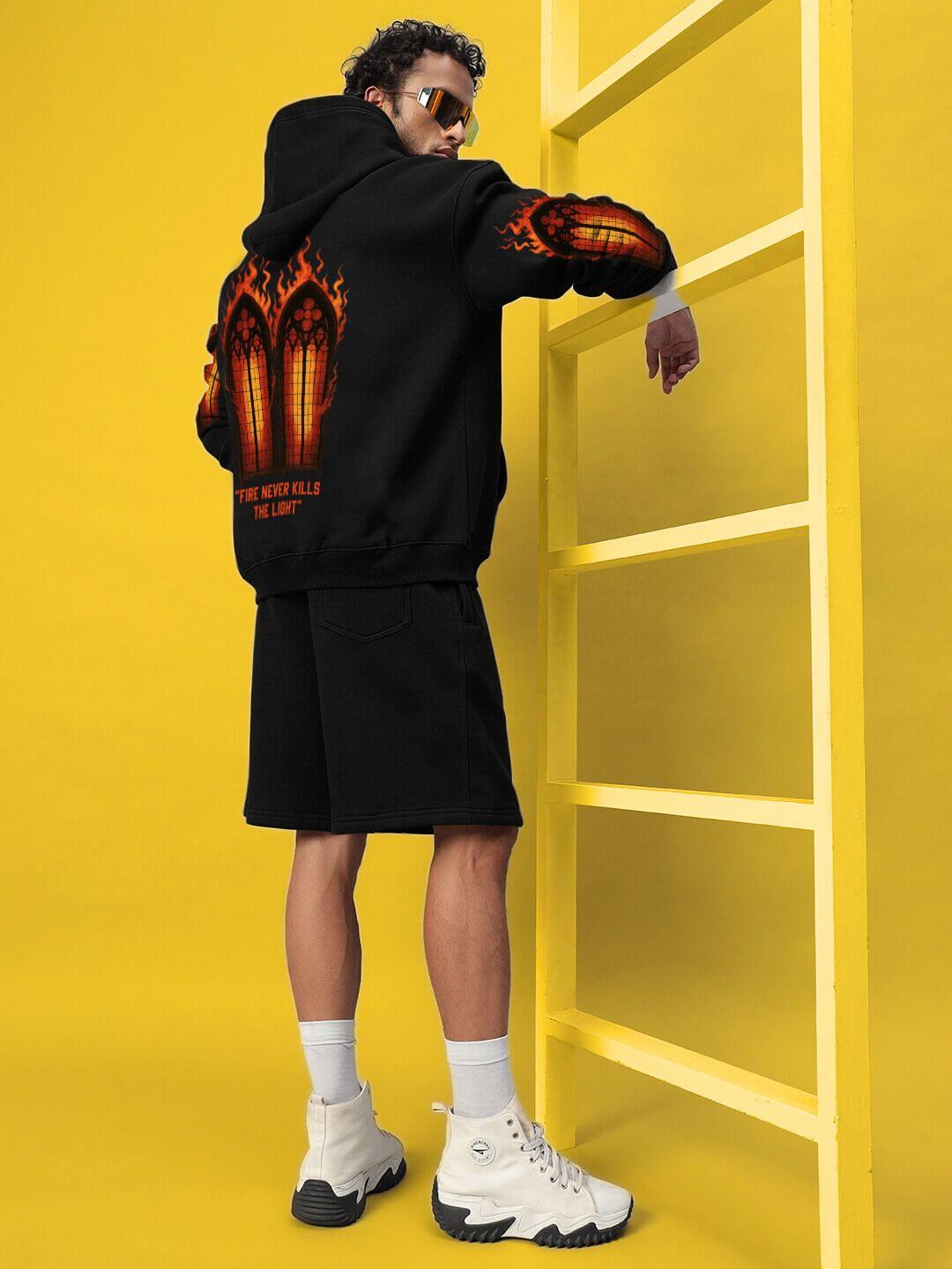 Model wearing FIRE NEVER KILLS THE LIGHT FLEECE CO-ORD BLACK, showcasing street-luxe style with bold graphics and cozy fleece material.