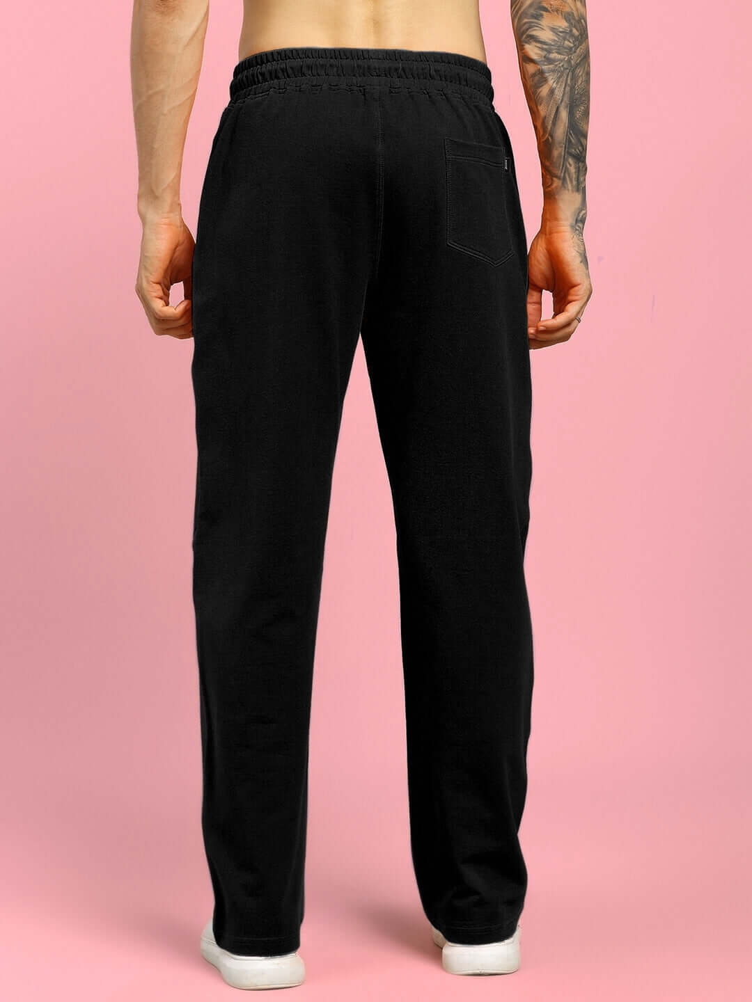 Back view of FLAMING SKELETON PRINTED RELAXED FIT JOGGER BLACK showcasing elastic waistband and relaxed fit on a pink background.
