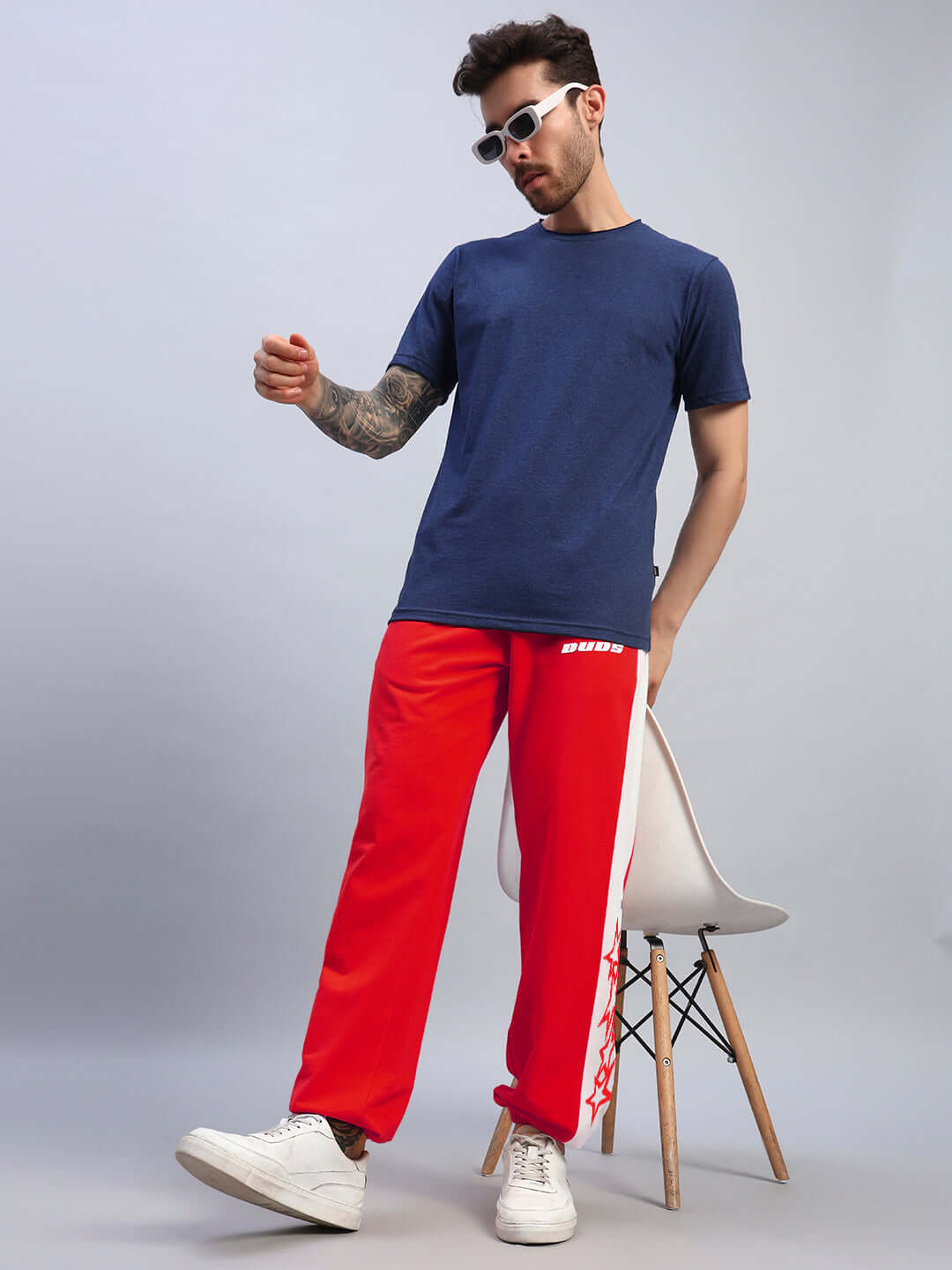 Man wearing Flash Relaxed Fit Joggers in Red-White, paired with a blue t-shirt and white sneakers, showcasing a casual sporty look.