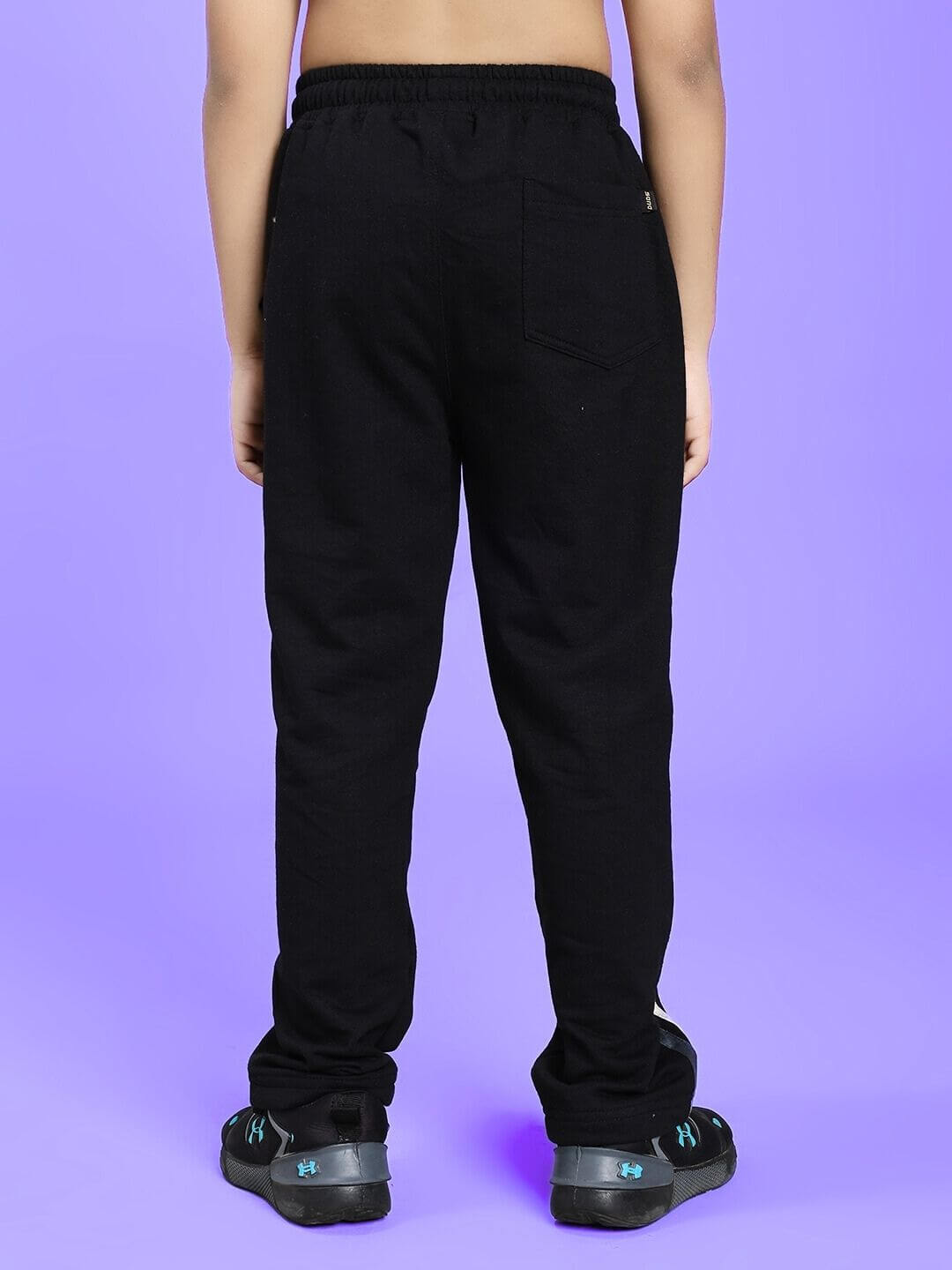 Child wearing FLICKER JOGGER FOR BOYS AND GIRLS BLACK shown from the back on a purple background.
