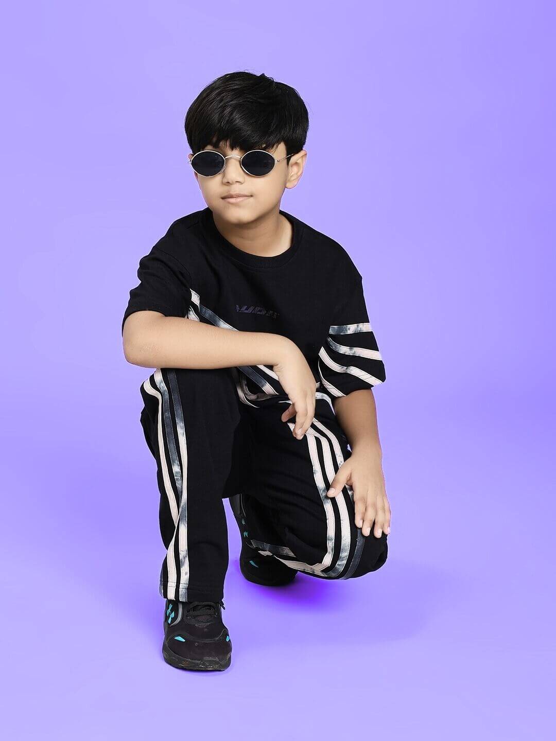 Boy wearing FLICKER DESIGNER OVERSIZED T-SHIRT FOR BOYS AND GIRLS BLACK with matching pants, sunglasses on a purple background
