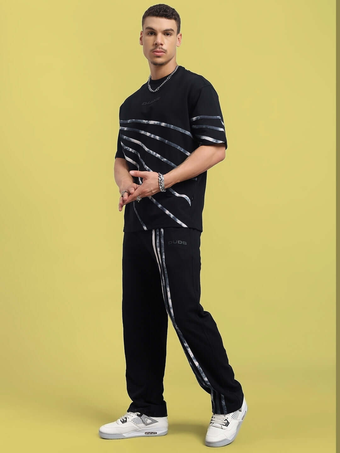 Model wearing black oversized co-ord set with relaxed fit joggers and drawstring waist, made of premium cotton-elastane blend.