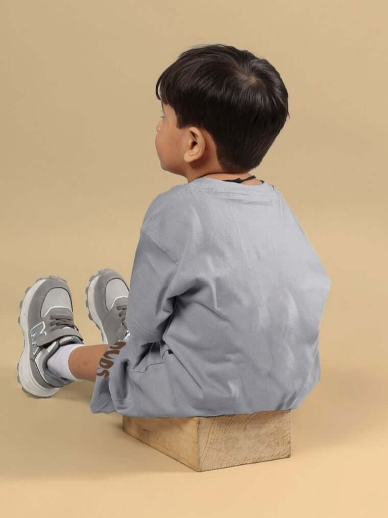 Child wearing FLINT BUNNY CO-ORD FOR BOYS AND GIRLS GREY, seated on a wooden block, showcasing trendy kids' fashion.