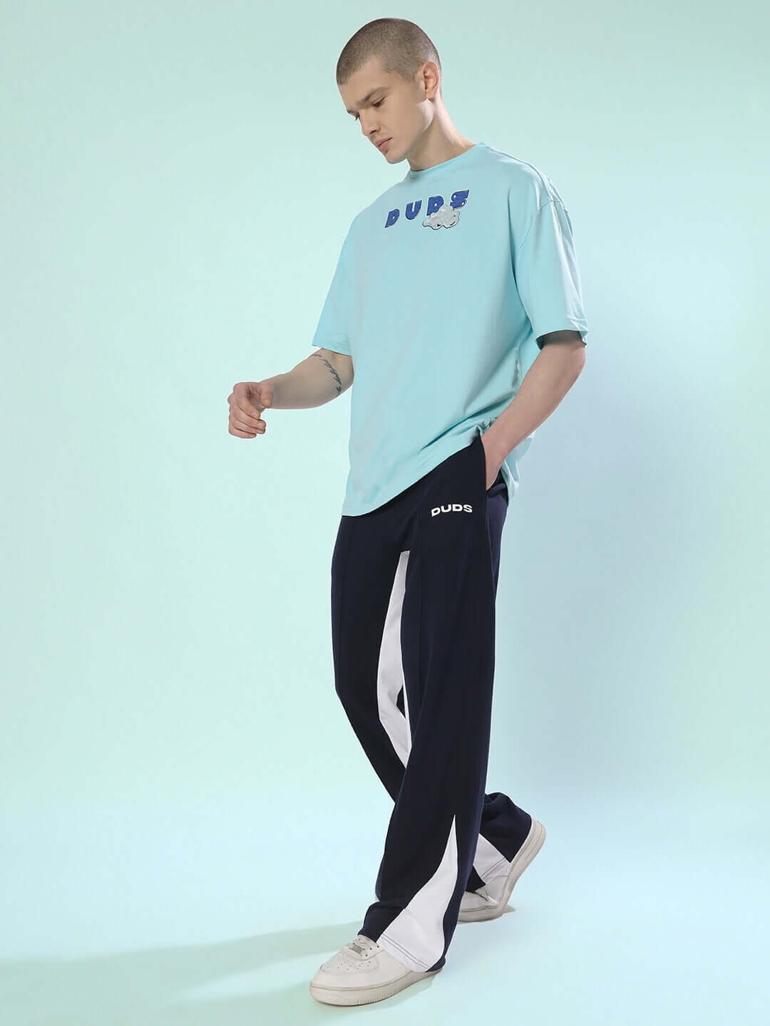 Model wearing floppy flared contrast joggers in navy blue with a casual light blue t-shirt.