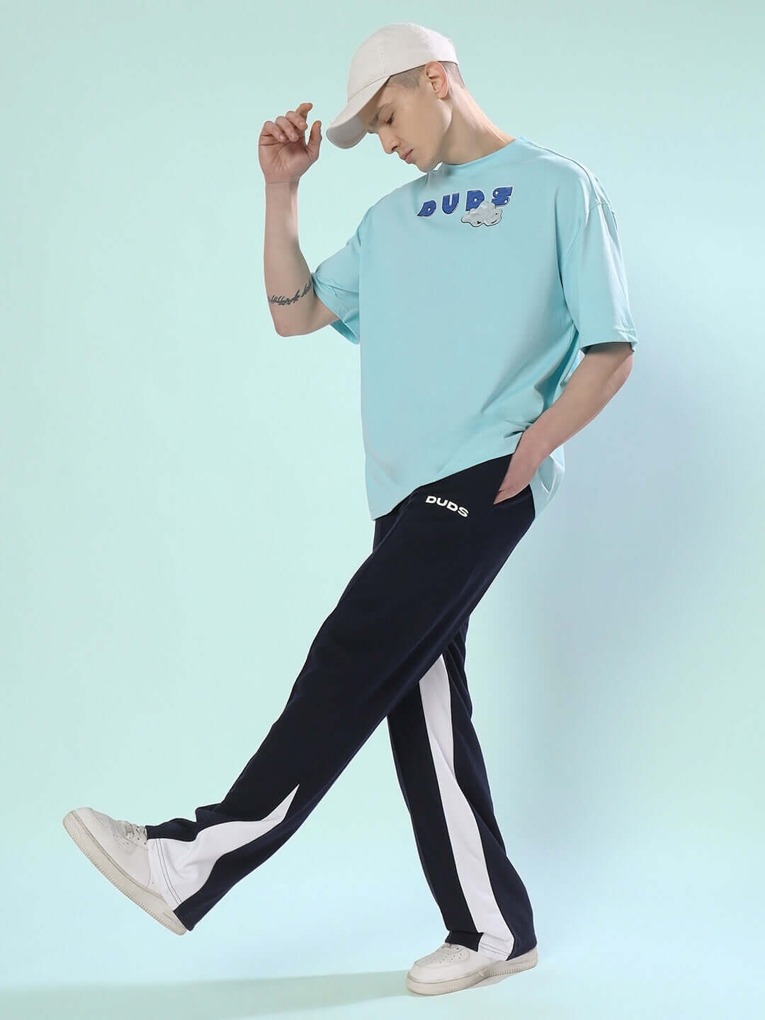 Model wearing DUDS contrast joggers in navy blue with a casual tee and white sneakers, showcasing stylish and comfortable athleisure wear.