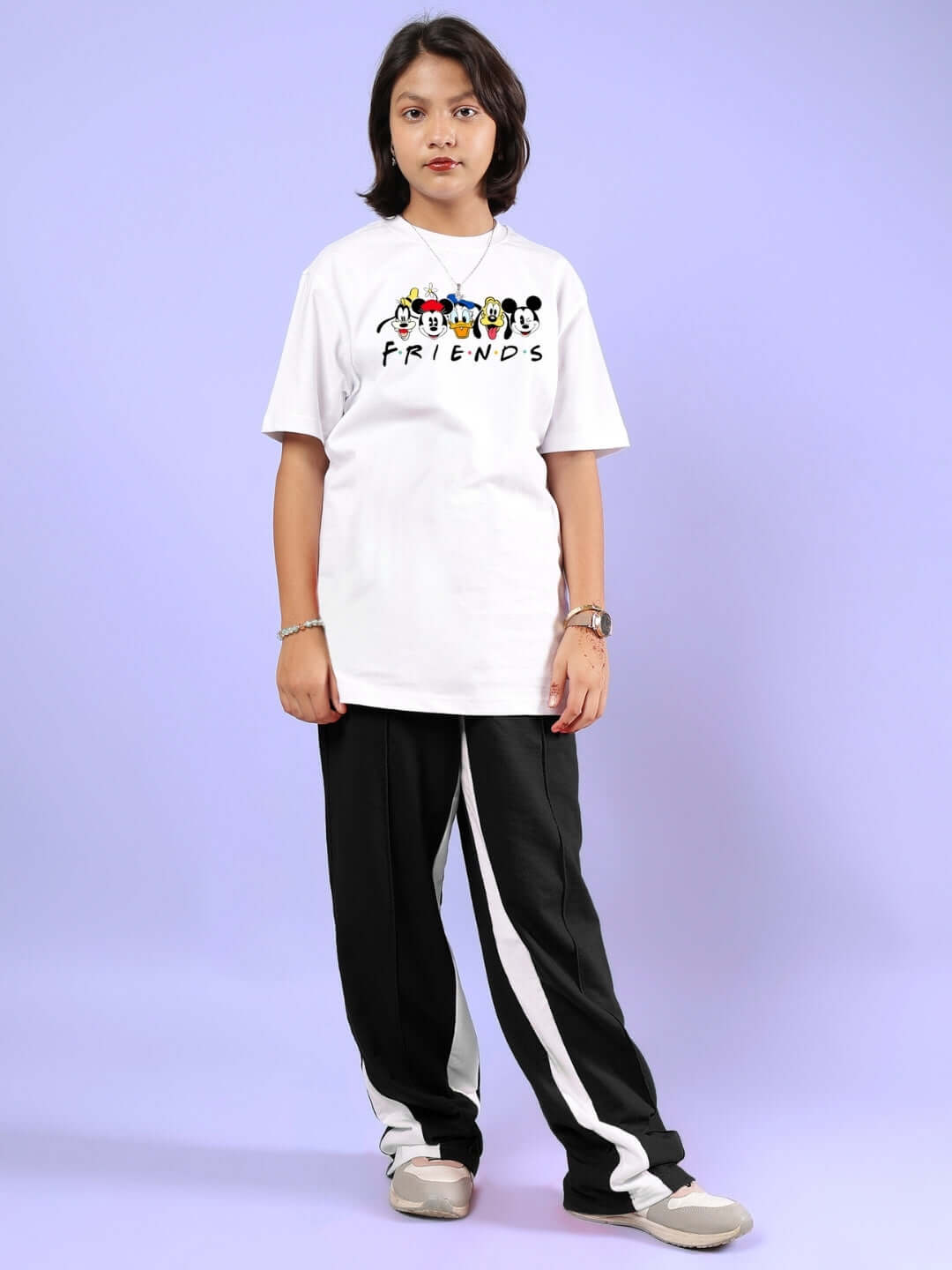Child wearing FLOPPY JOGGER FOR BOYS & GIRLS BLACK with a white Friends t-shirt against a purple background.