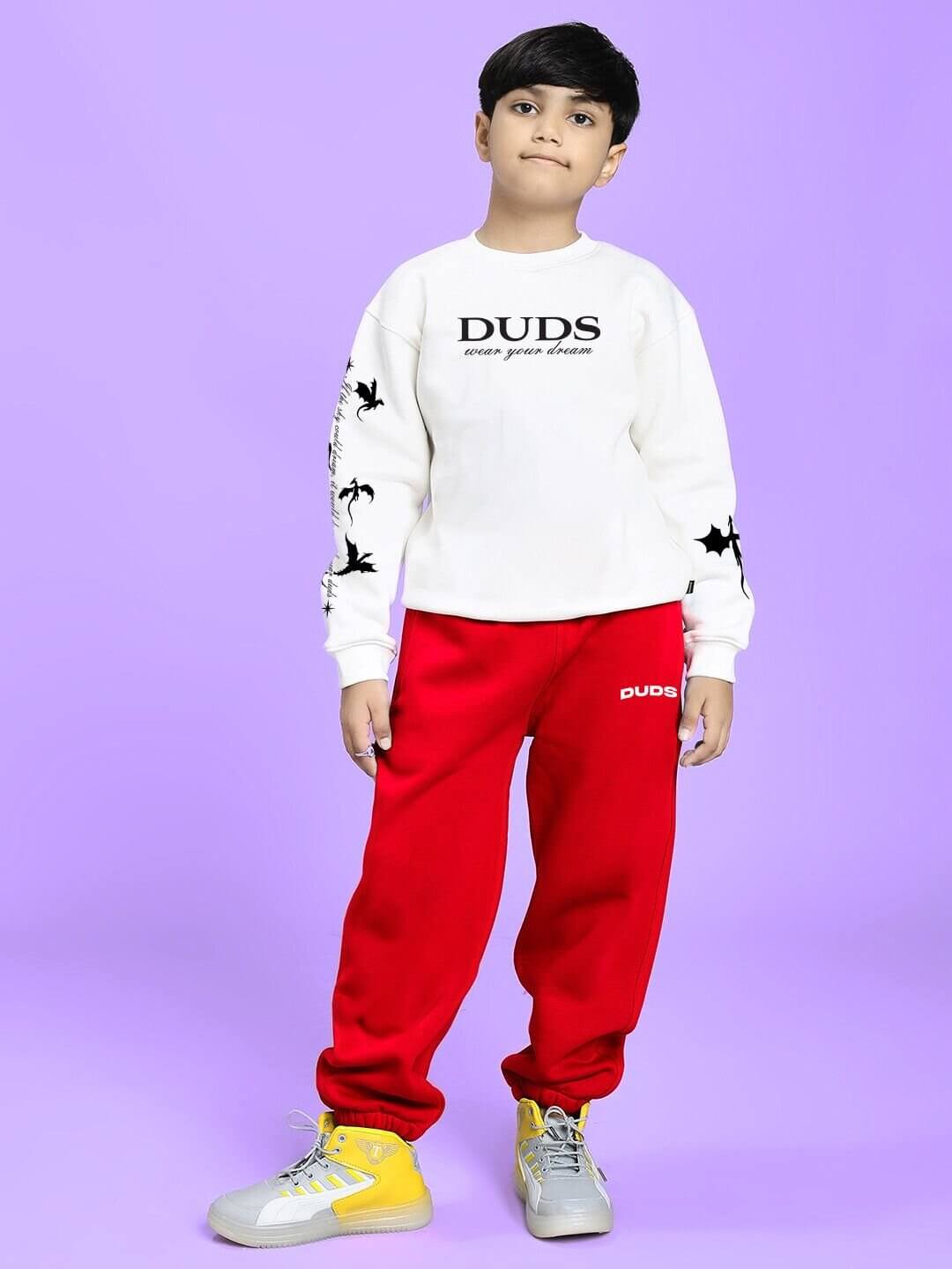 Boy wearing FLY OR DIE DRAGON FLEECE CO-ORD FOR BOYS AND GIRLS WHITE RED, standing confidently against a purple background