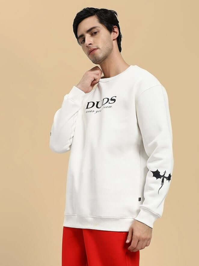 Man wearing FLY OR DIE DRAGON PRINT FLEECE SWEATSHIRT OFF WHITE with dragon motif, streetwear fashion.