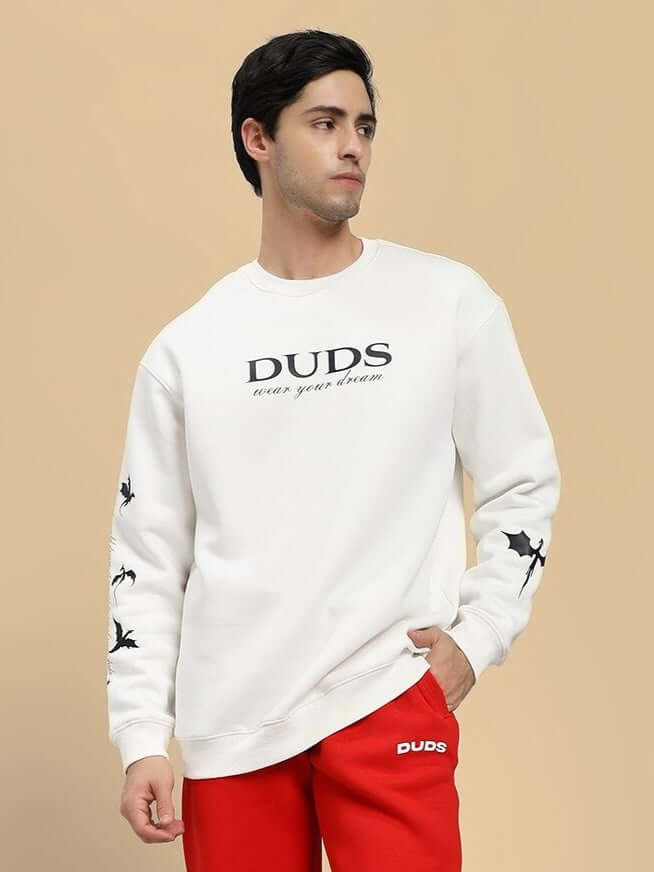 Model wearing FLY OR DIE DRAGON PRINT FLEECE SWEATSHIRT OFF WHITE with bold dragon motifs on sleeves.