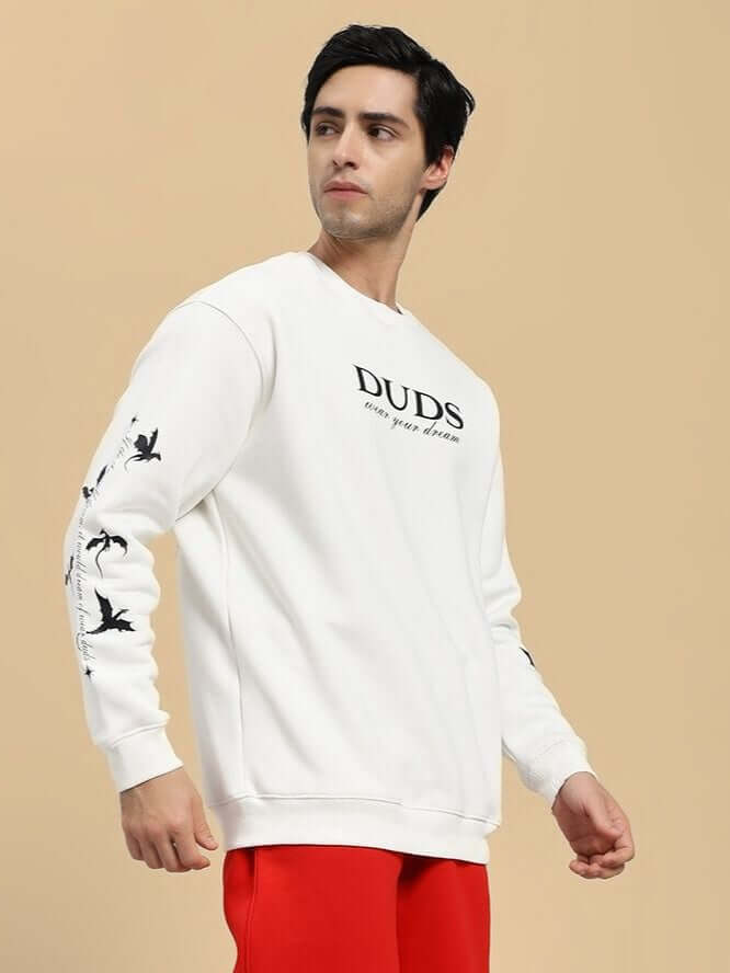 Man wearing FLY OR DIE DRAGON PRINT FLEECE SWEATSHIRT OFF WHITE with dragon motif, streetwear fashion