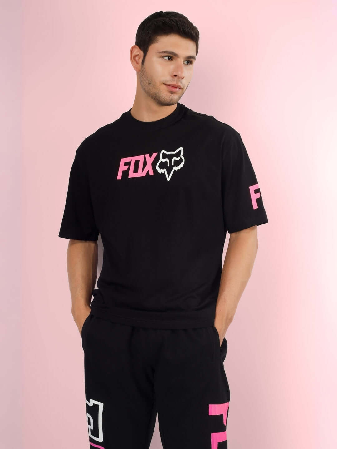 Model wearing black FOX over-sized t-shirt with pink accents, featuring logo and custom fit options for personalized sizing.