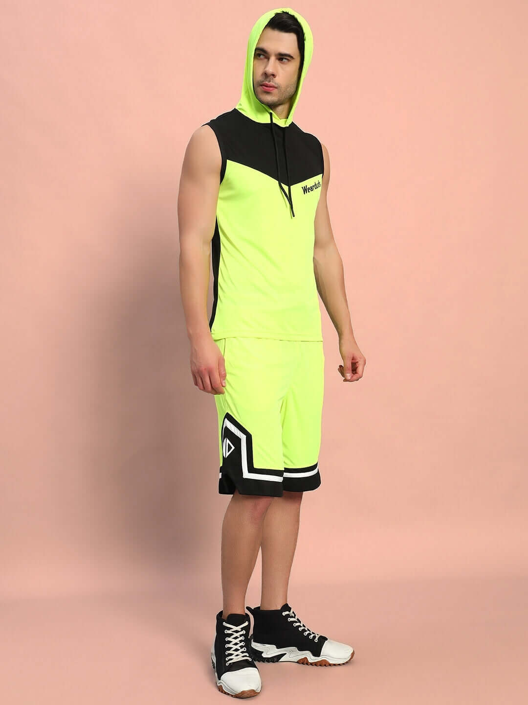 Man wearing FRANKY GYM CO-ORD SET NEON GREEN with hood, showcasing athletic style and vibrant performance apparel against a pink backdrop.