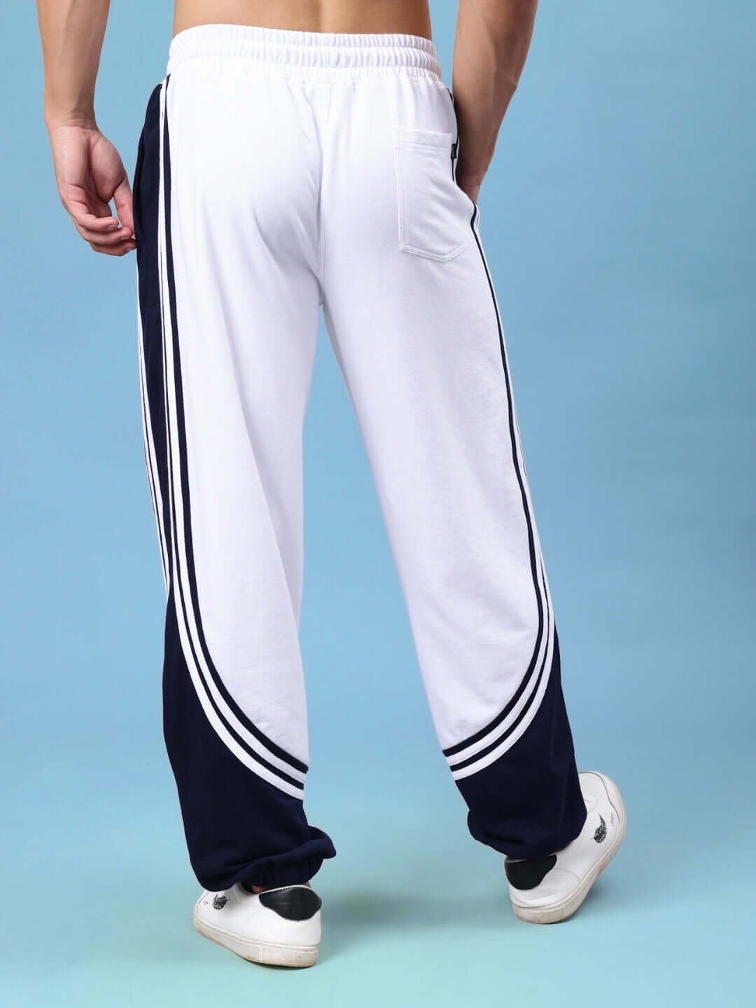 Back view of white and navy contrast joggers, featuring curved design, worn by model, showcasing comfortable fit and style by DUDS.