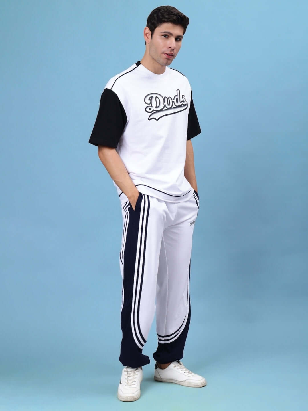 Model wearing Frenzy Curve Contrast Joggers in white-navy with DUDS branding backdrop.