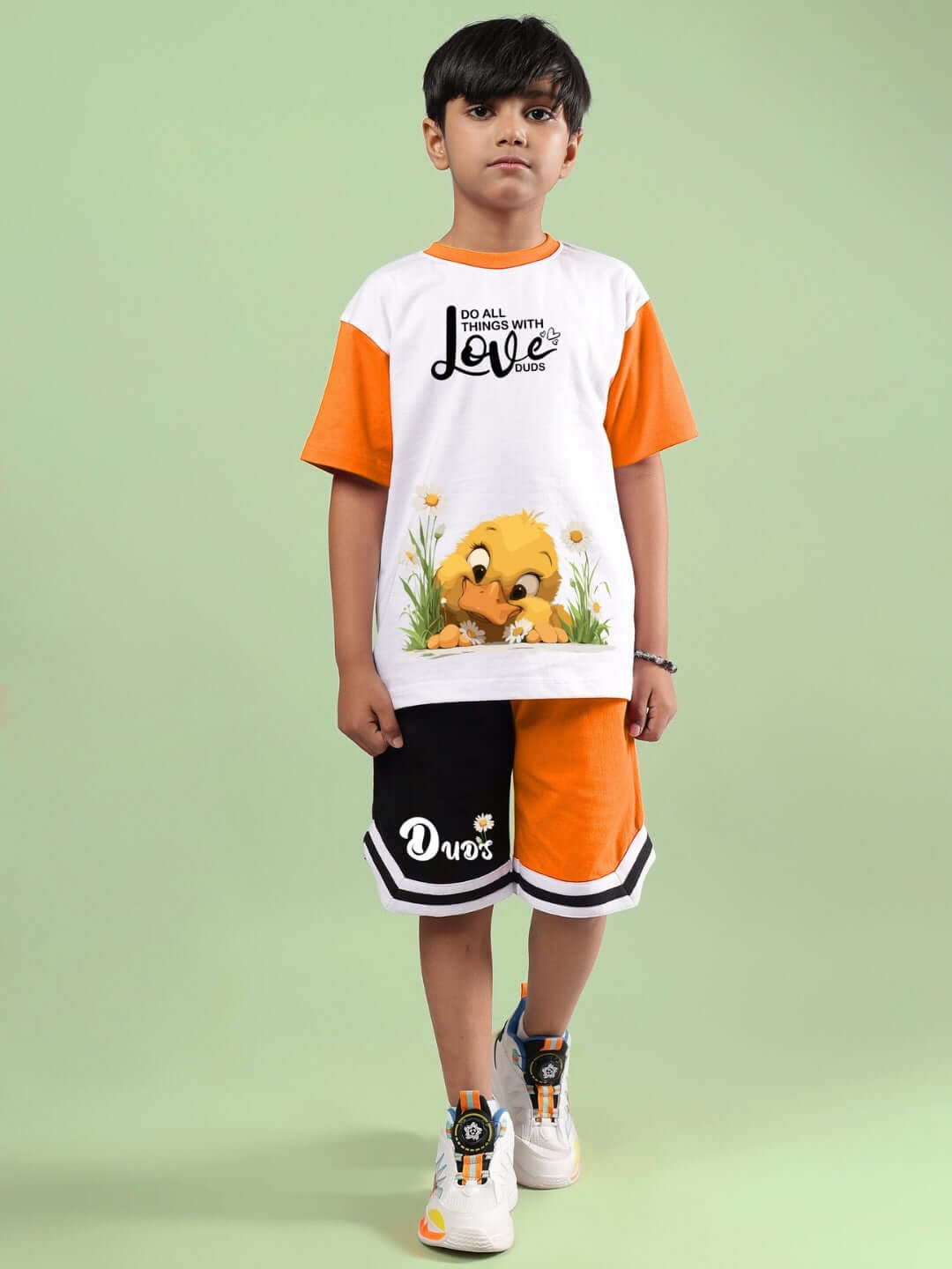 FRIENDSHIP BUCKET CO-ORD FOR BOYS & GIRLS WHITE ORANGE outfit by DUDS, featuring a child wearing the co-ord set with a duck print, on a green background.