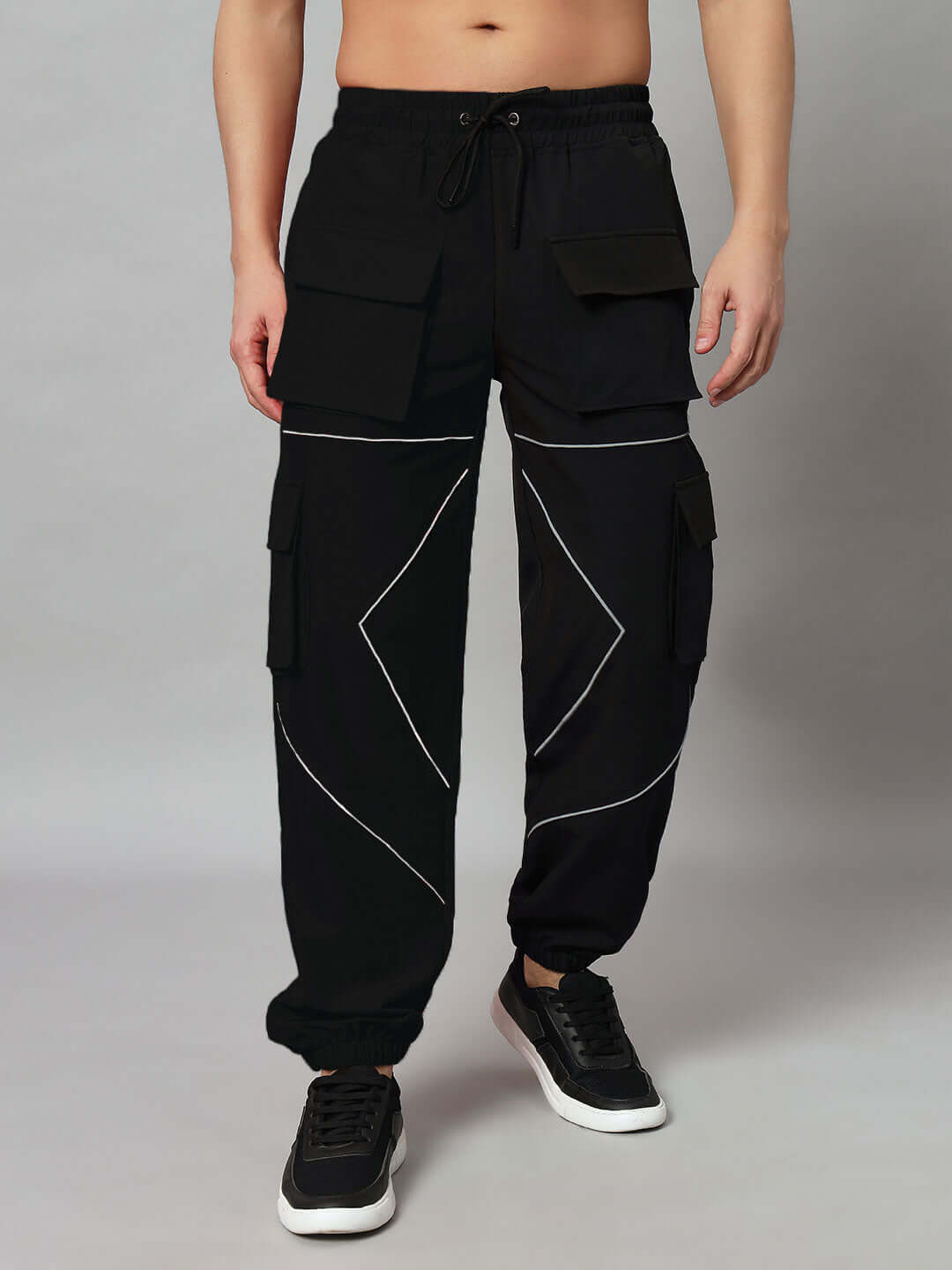 Model wearing FRONTLINE REFLECTOR PARACHUTE CARGO PANT BLACK with reflective accents, showcasing high-impact style and utility.
