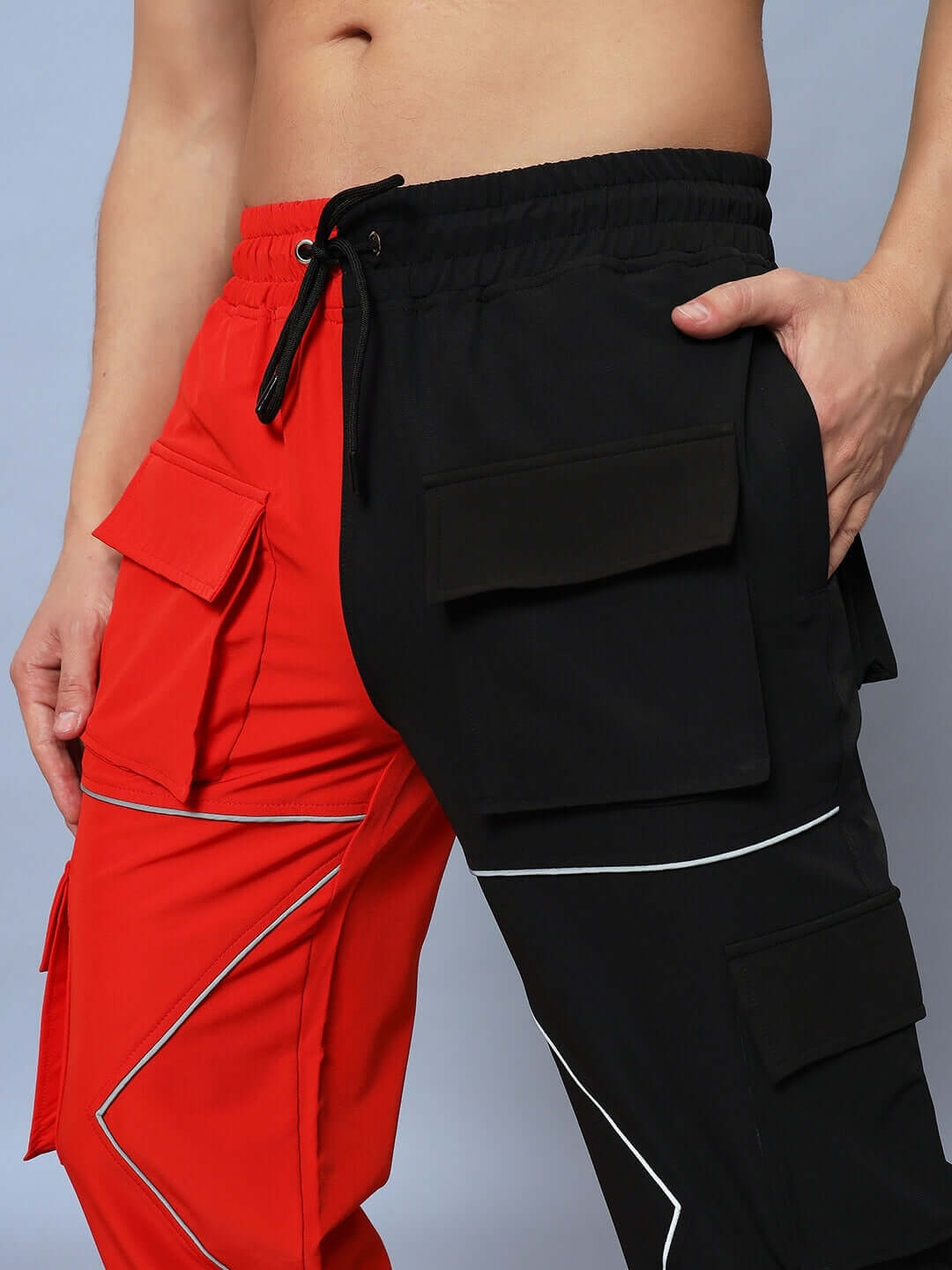 Close-up of red and black Frontline Reflector Parachute Cargo Pants with custom fit option from DUDS, featuring side pockets.