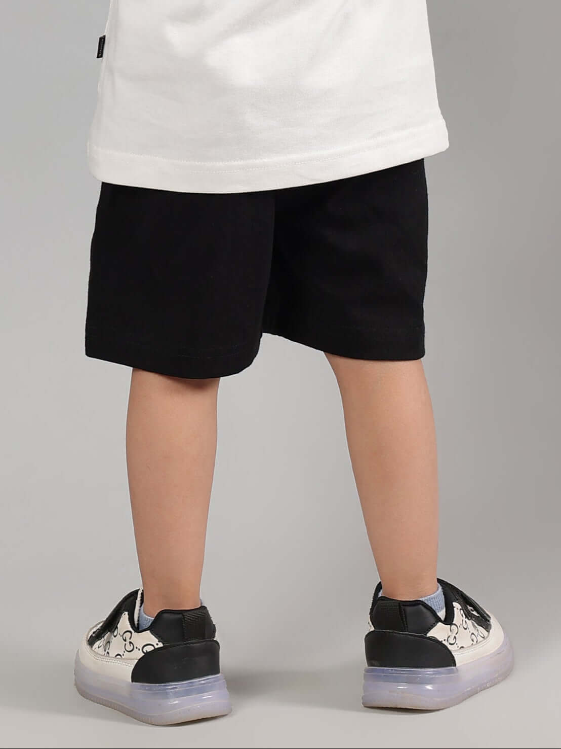 Child wearing black summer shorts, part of DUDS' made-to-order collection, suitable for boys and girls. Available with custom fit option.