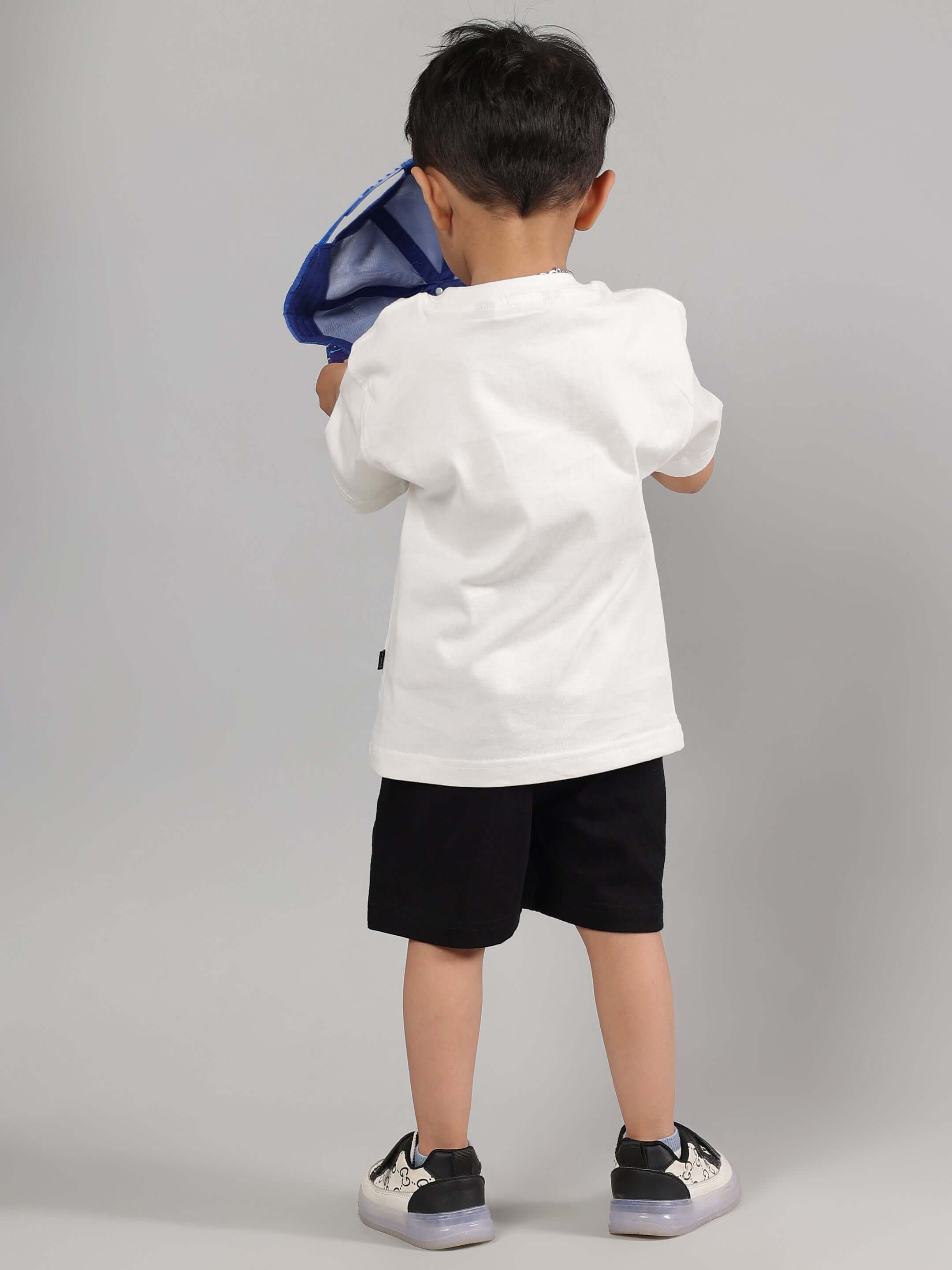 Child wearing FULNESS PARADISE CO-ORD FOR BOYS GIRLS OFF WHITE-BLACK outfit, facing away with a blue hat.