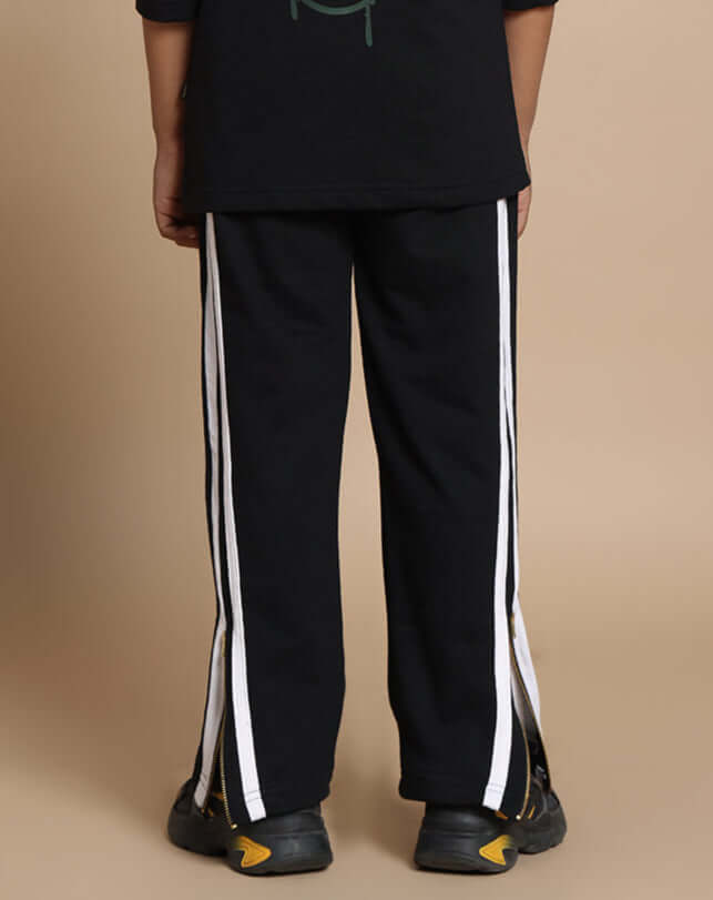 Child wearing black Fun-Babe joggers with white stripes, tailored by DUDS, showing the back view of the pants for boys and girls.