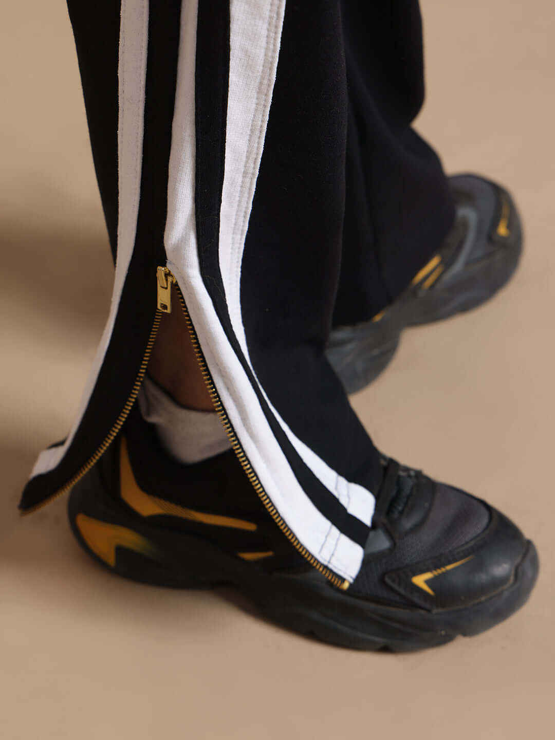 Close-up of black Fun-Babe joggers with white stripes and zip detail, paired with black and yellow sneakers for boys and girls.