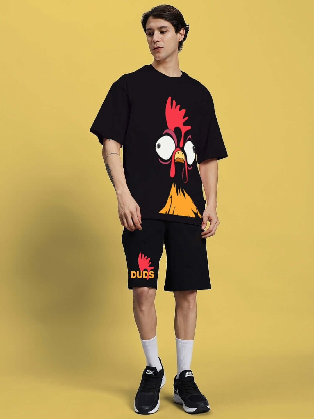 Man wearing FUNNY CHICKEN SUMMER CO-ORD SET BLACK with quirky chicken print, yellow background