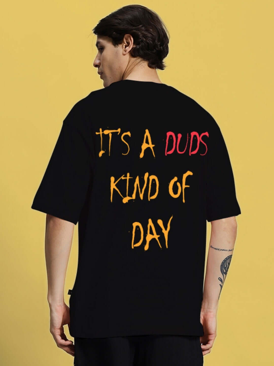 Back view of model wearing a black oversized t-shirt with colorful text, "IT'S A DUDS KIND OF DAY".