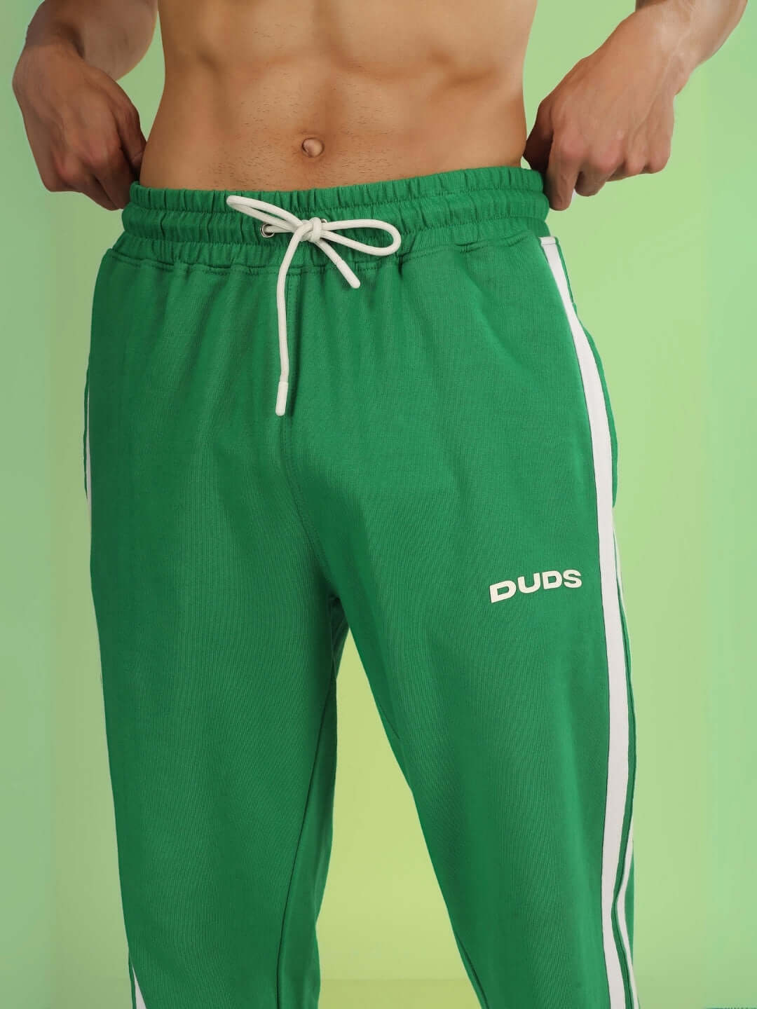 Model wearing green FUTURE ICON 2 STRIPE JOGGER by DUDS showing elastic waist and side stripes against a green background.