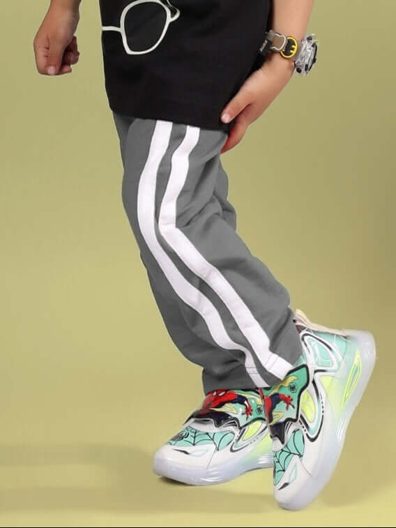 Child wearing grey FUTURE ICON jogger pants with white stripes and colorful sneakers.